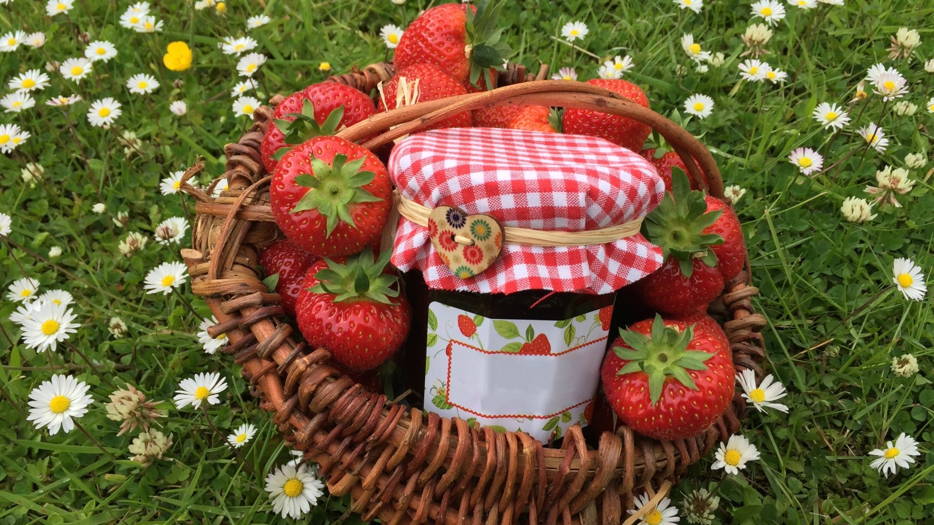 Basket of strawberries and jam jar on grass with daisies HD Wallpaper