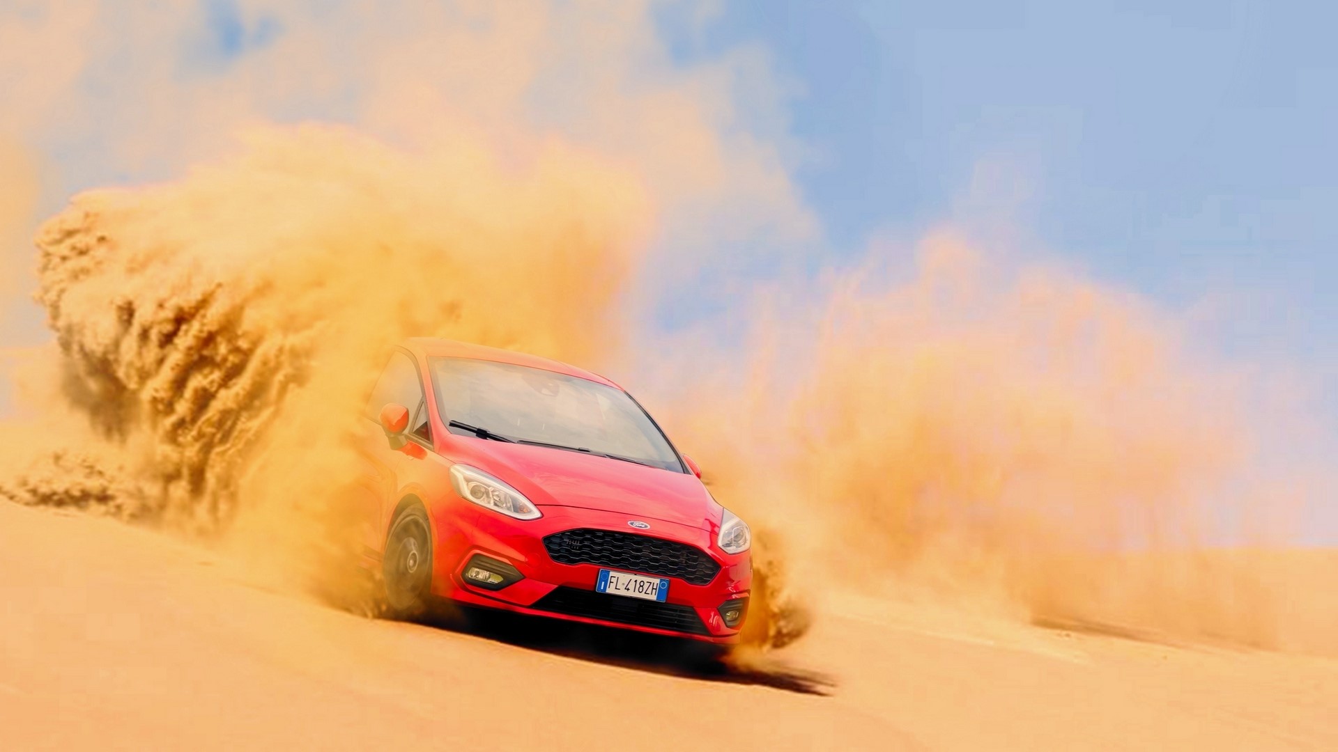 Red Ford Fiesta driving through sand dunes HD Wallpaper