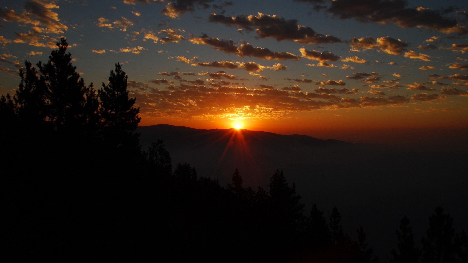 Sunset over mountains with clouds and trees HD Wallpaper