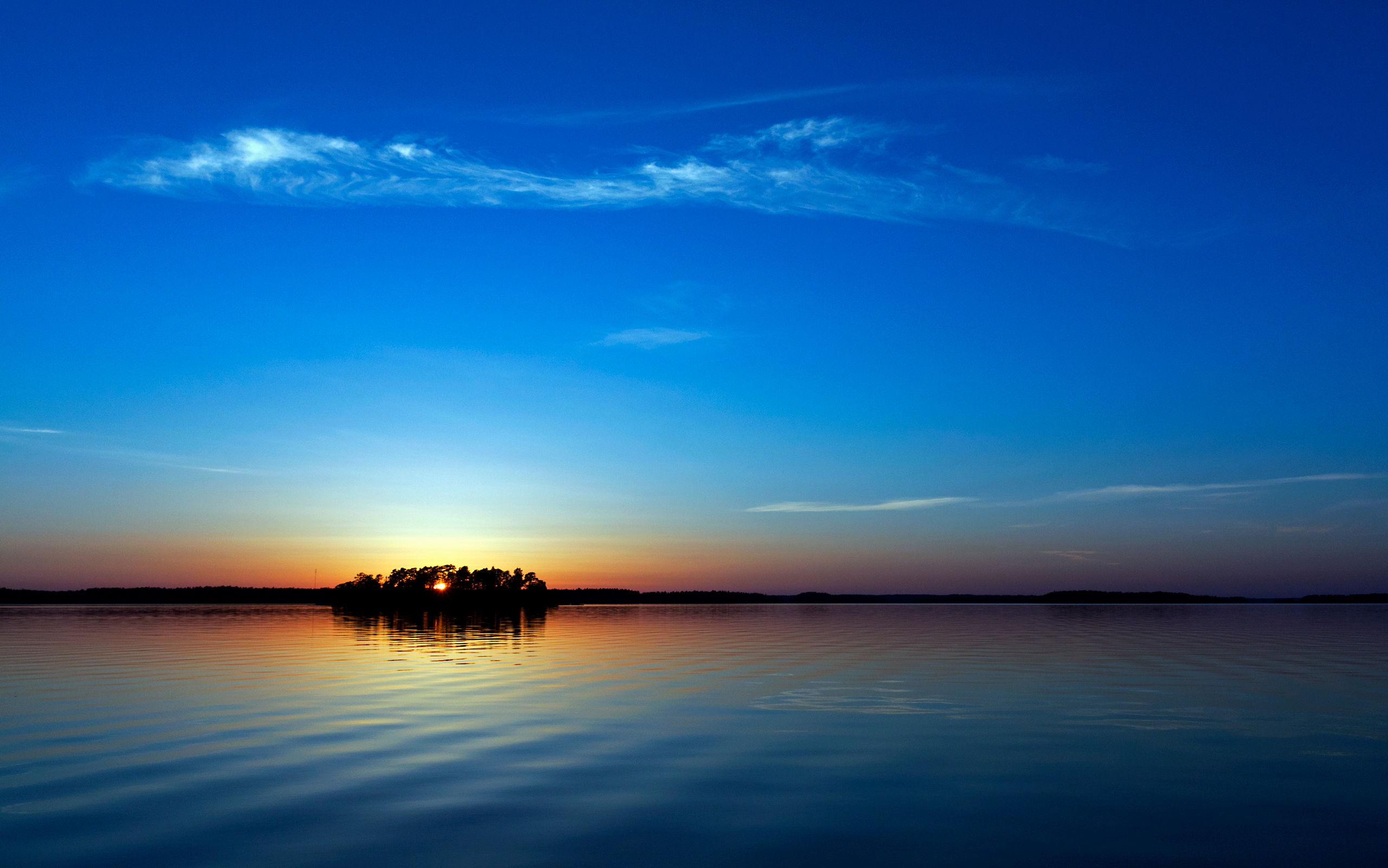 Island silhouette at sunset over calm water HD Wallpaper