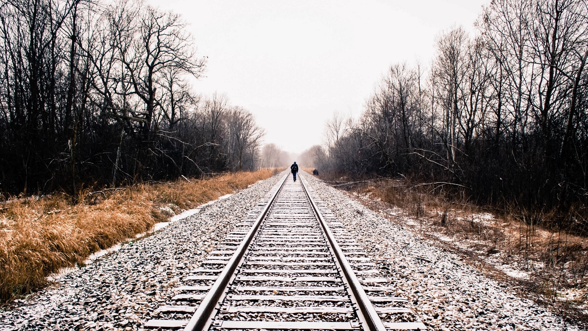 Person walking on railroad tracks in winter HD Wallpaper