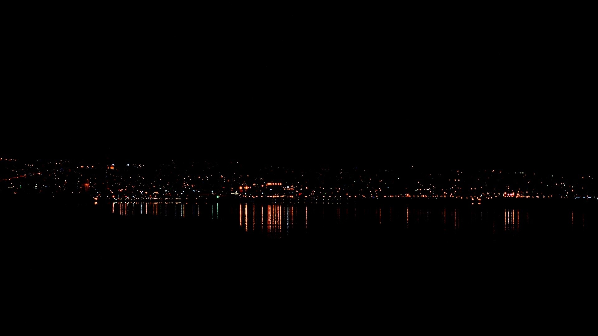 City lights reflecting on water at night HD Wallpaper