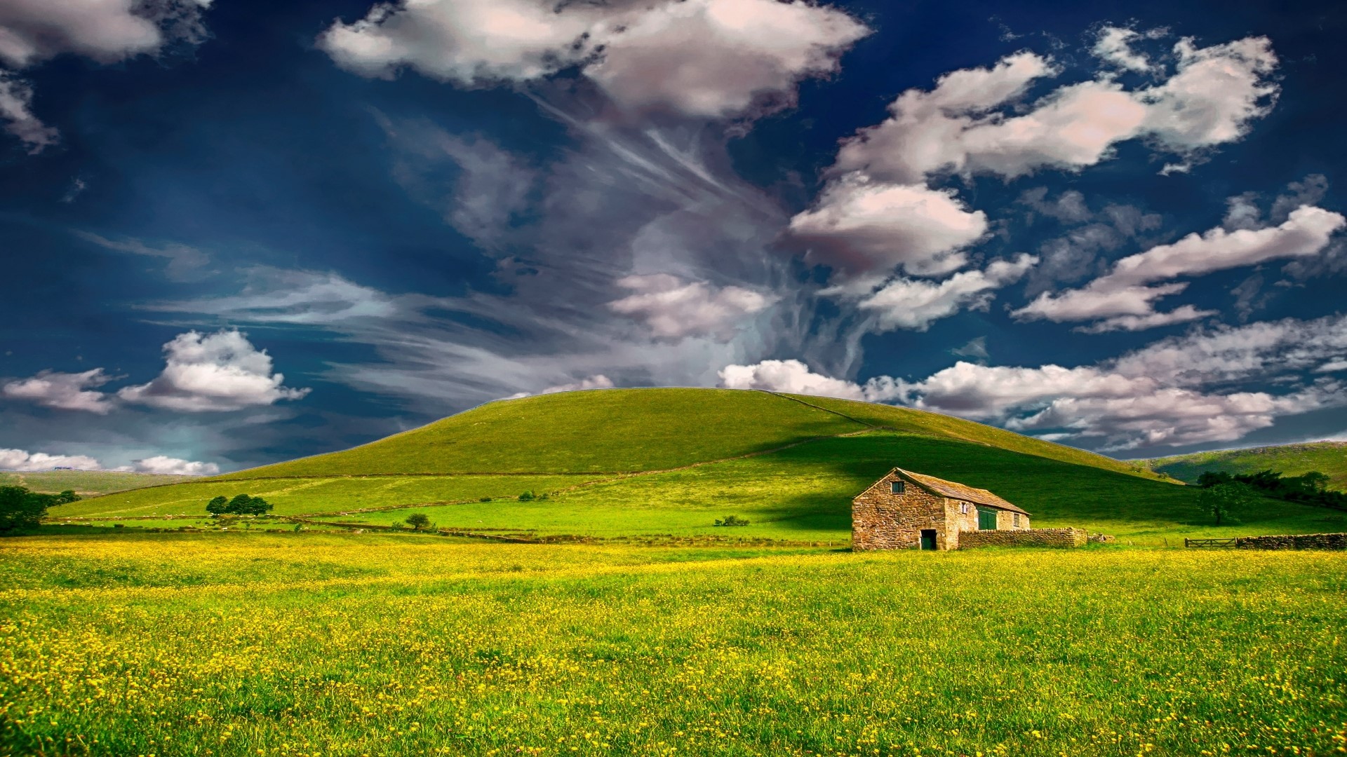 Stone barn in a green field under a cloudy sky HD Wallpaper