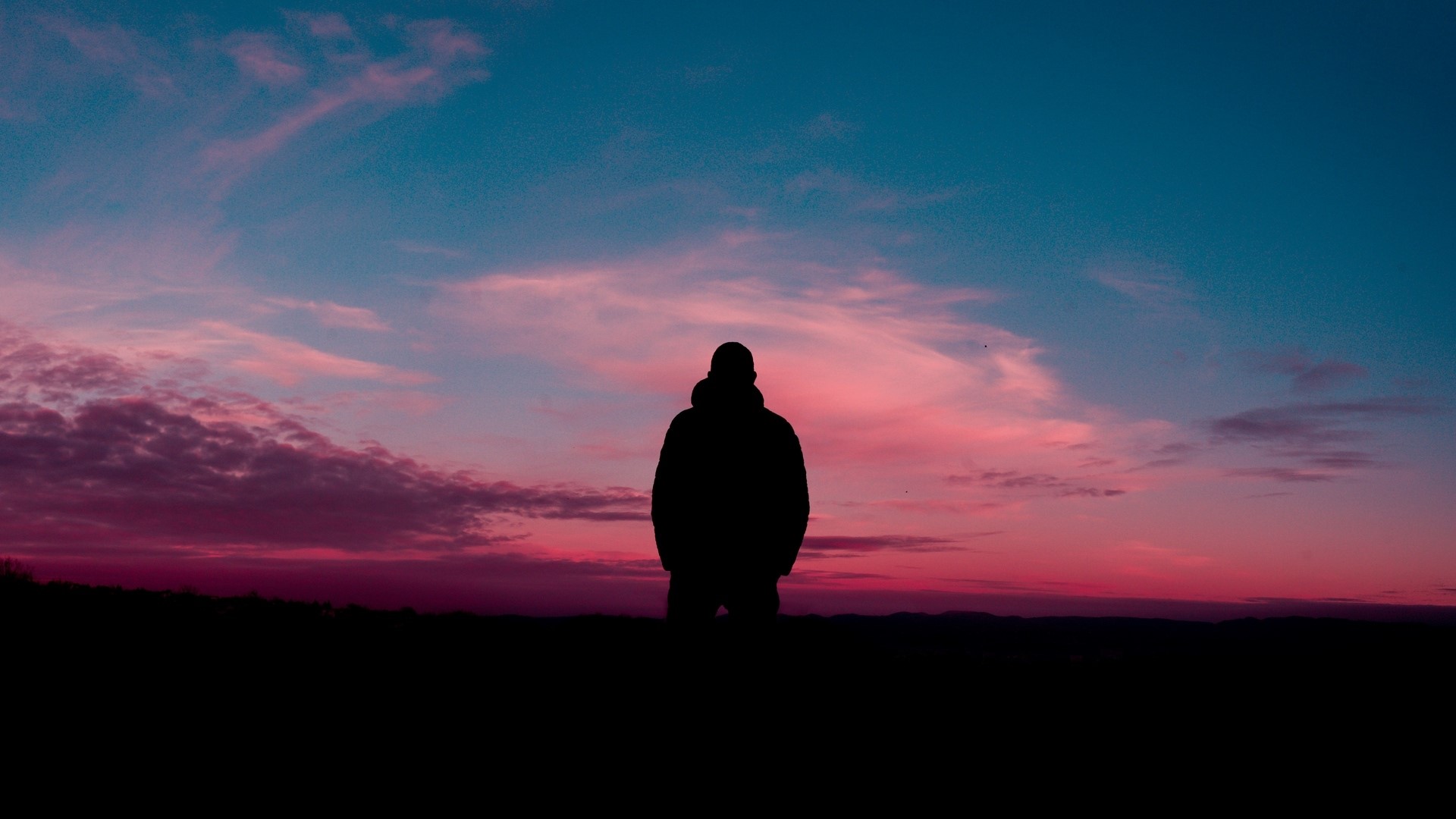 Silhouette of a person against a colorful sunset sky HD Wallpaper