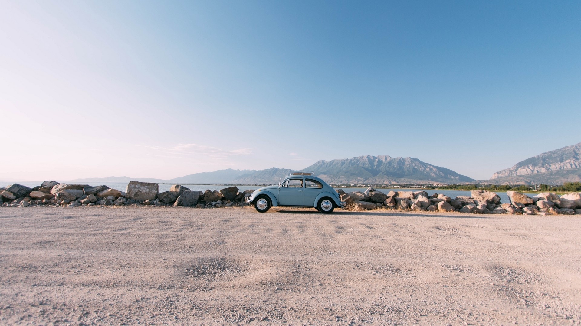 Blue Volkswagen Beetle by a lake with mountains HD Wallpaper