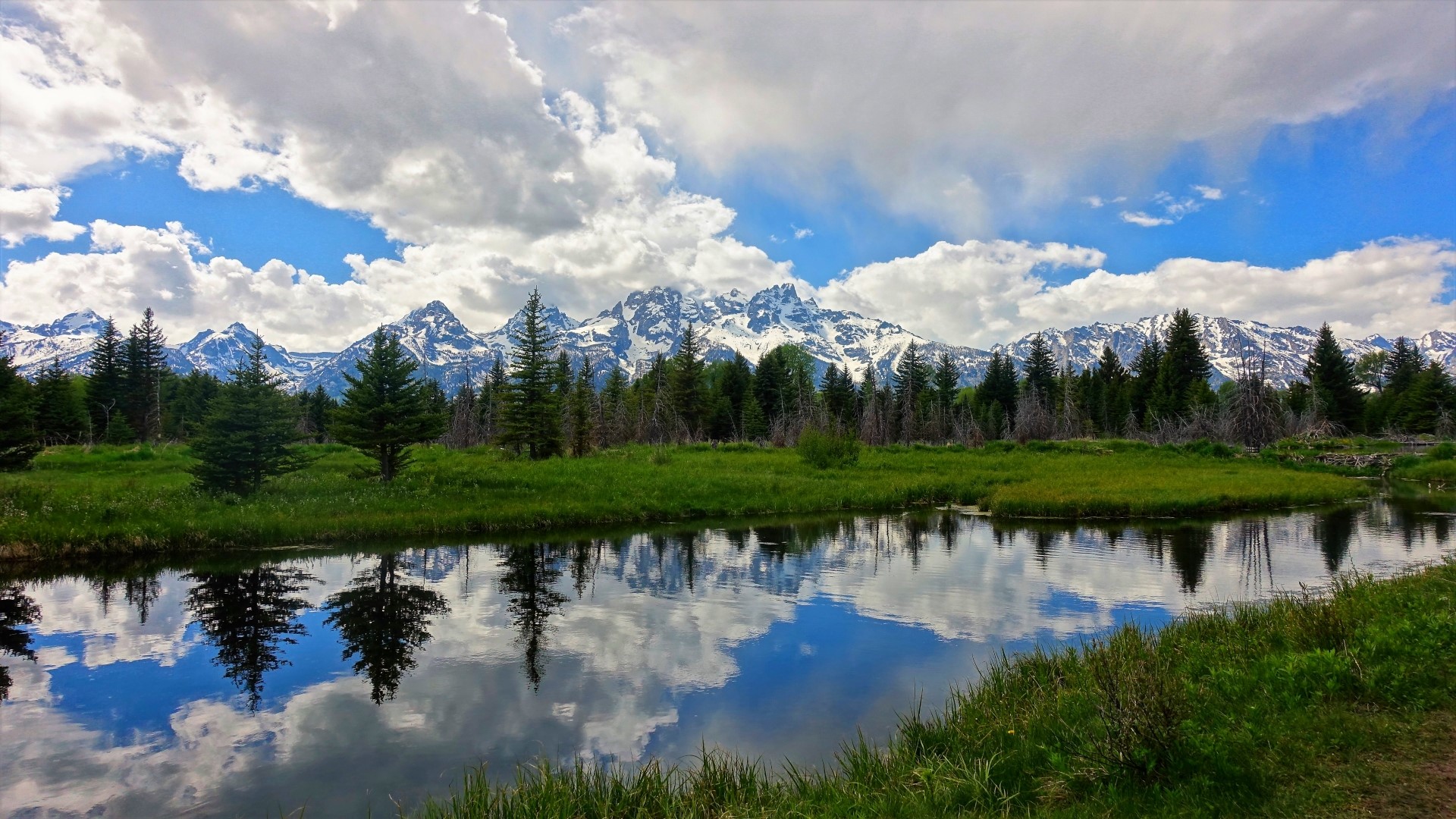 Snow-capped mountains reflected in a calm river HD Wallpaper