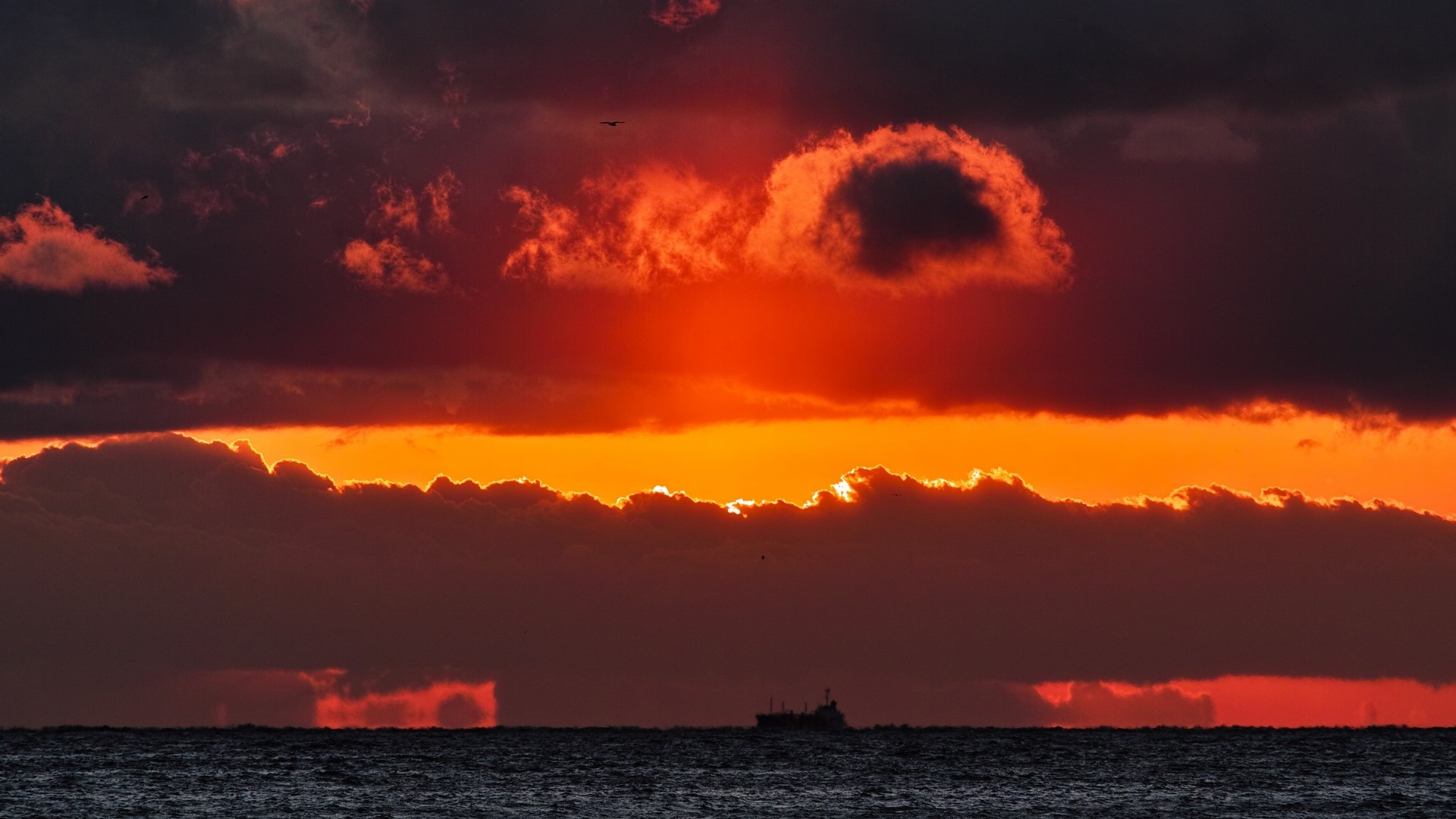 Dramatic sunset over the ocean with a ship HD Wallpaper