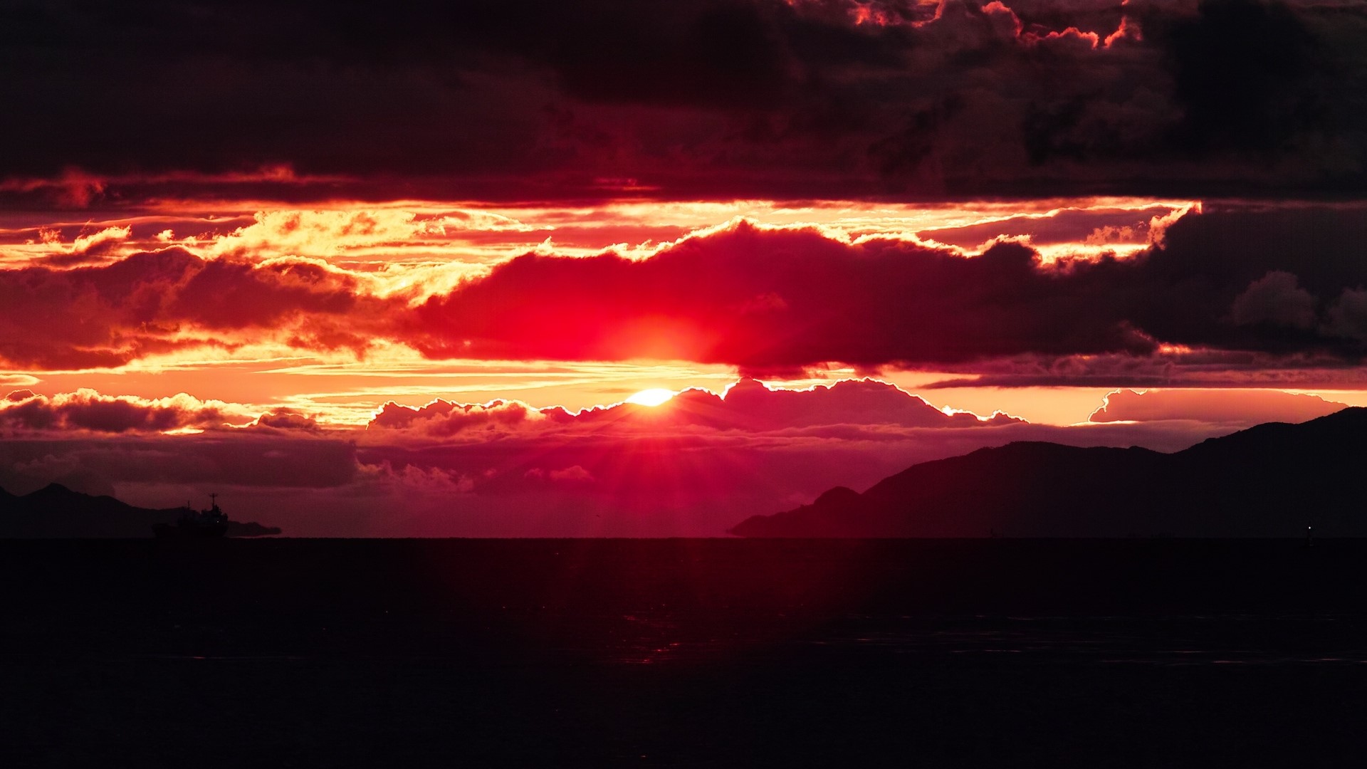 Dramatic Sunset Over Ocean with Mountains and Ship HD Wallpaper