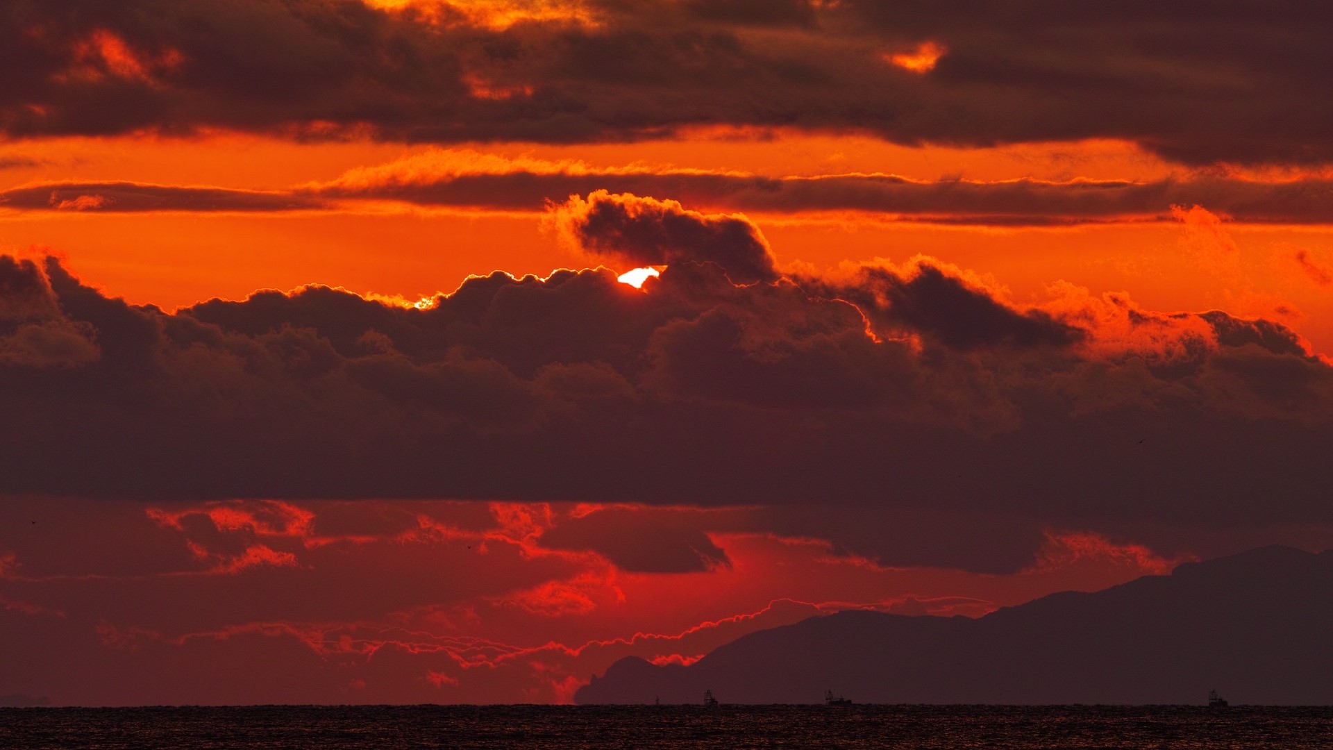Sunset over the ocean with clouds and mountains HD Wallpaper