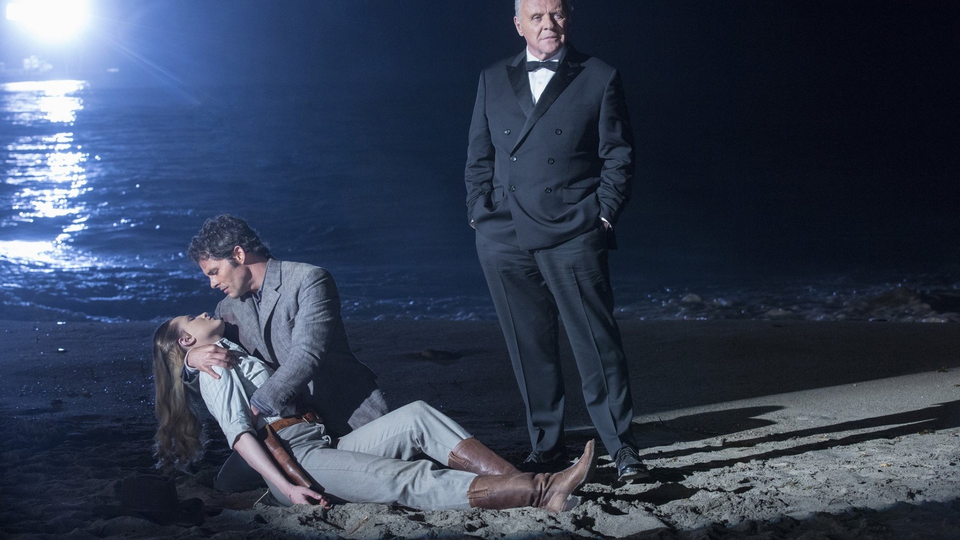 Man holding woman on beach with man in tuxedo HD Wallpaper