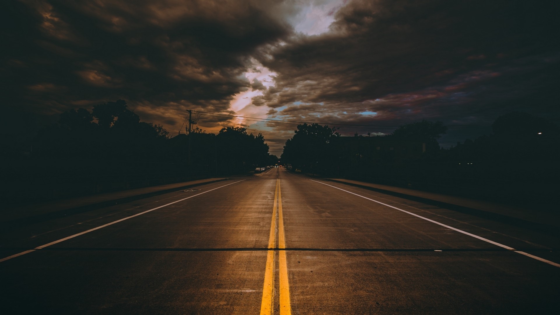 Empty road with double yellow lines under stormy clouds HD Wallpaper