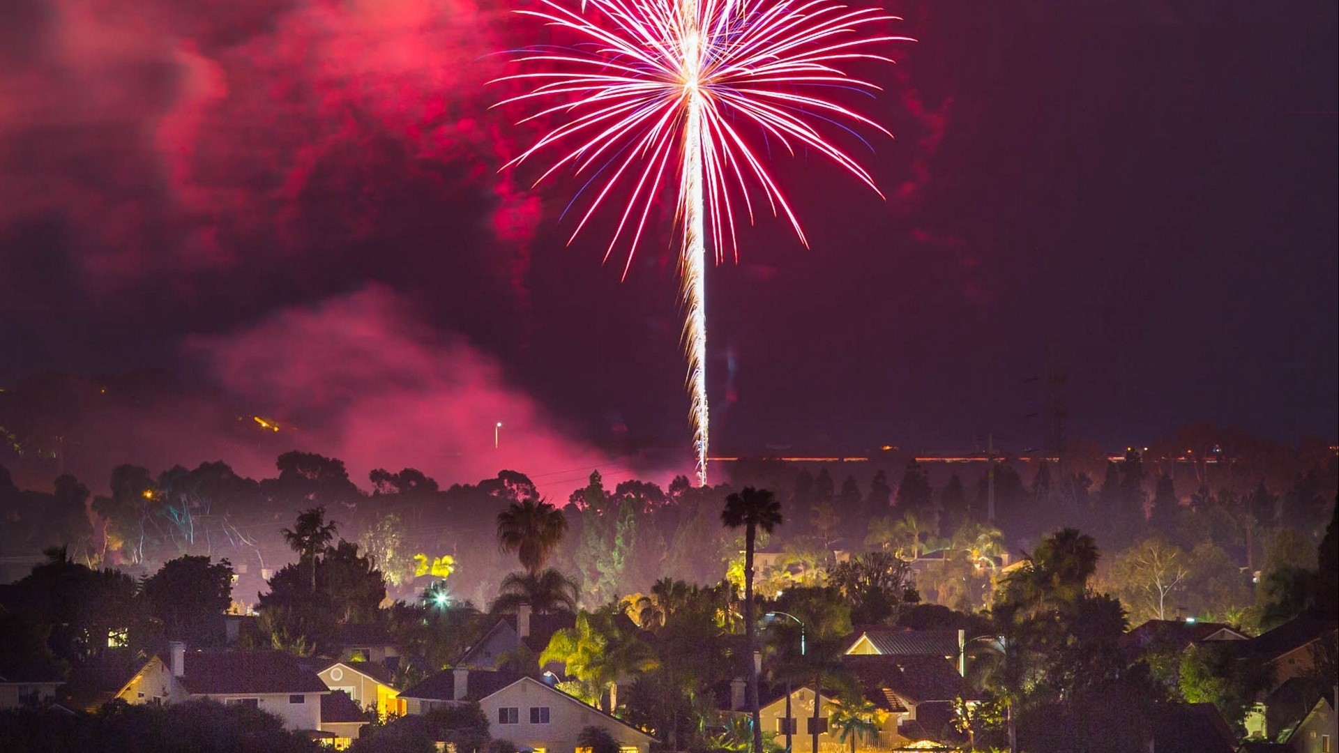 Fireworks over a suburban neighborhood at night HD Wallpaper