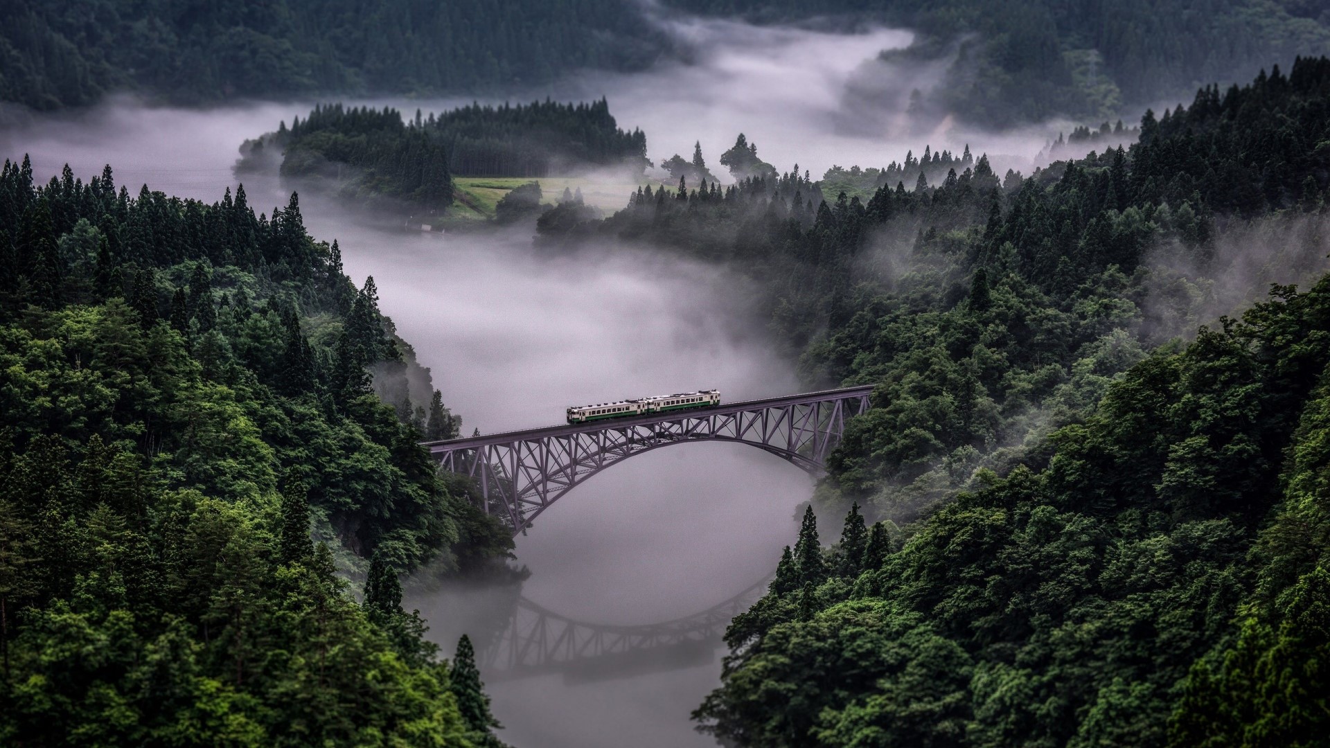 Train crossing a bridge in foggy mountains of Japan HD Wallpaper