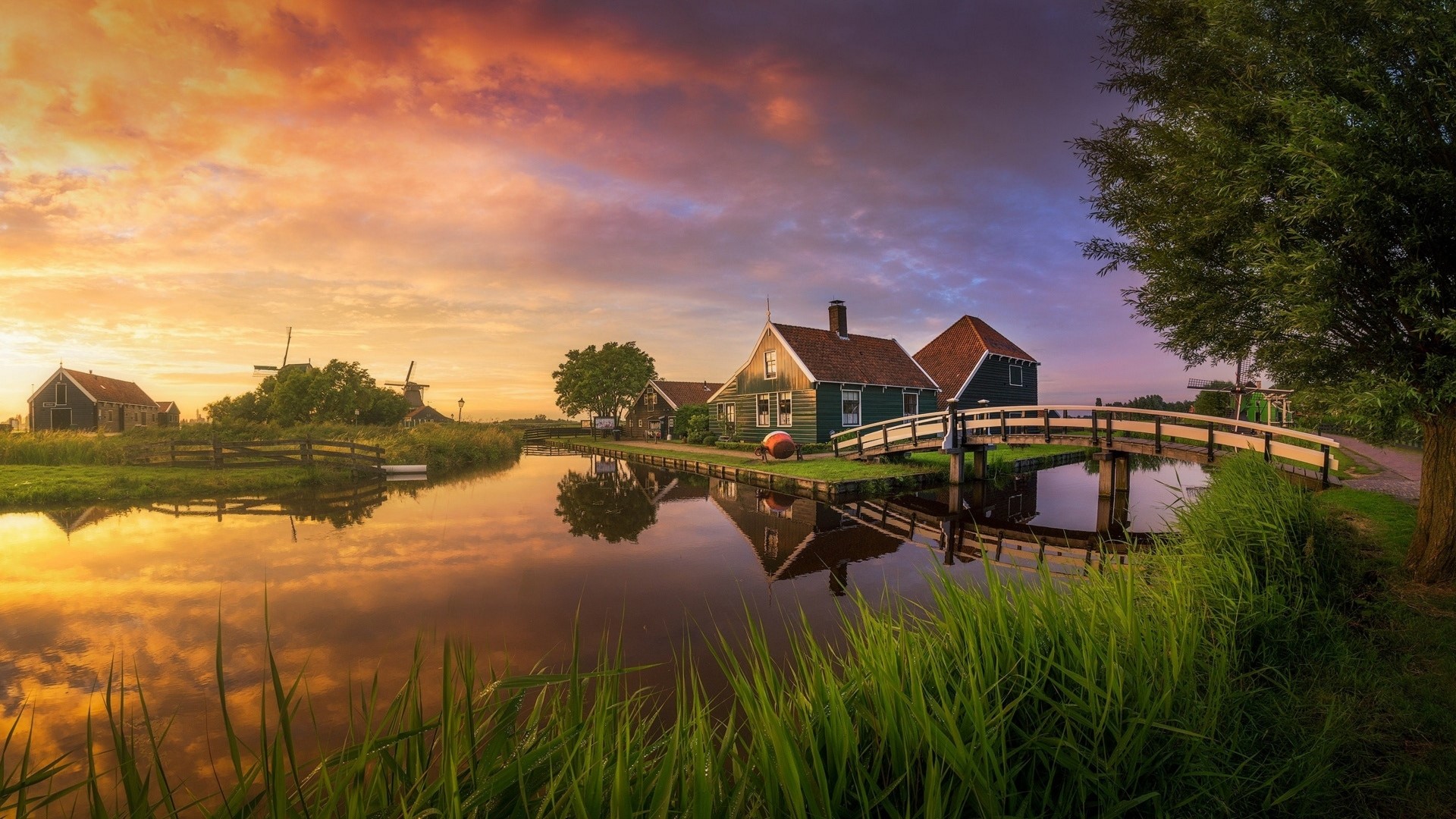Dutch windmills and houses by a canal at sunset HD Wallpaper