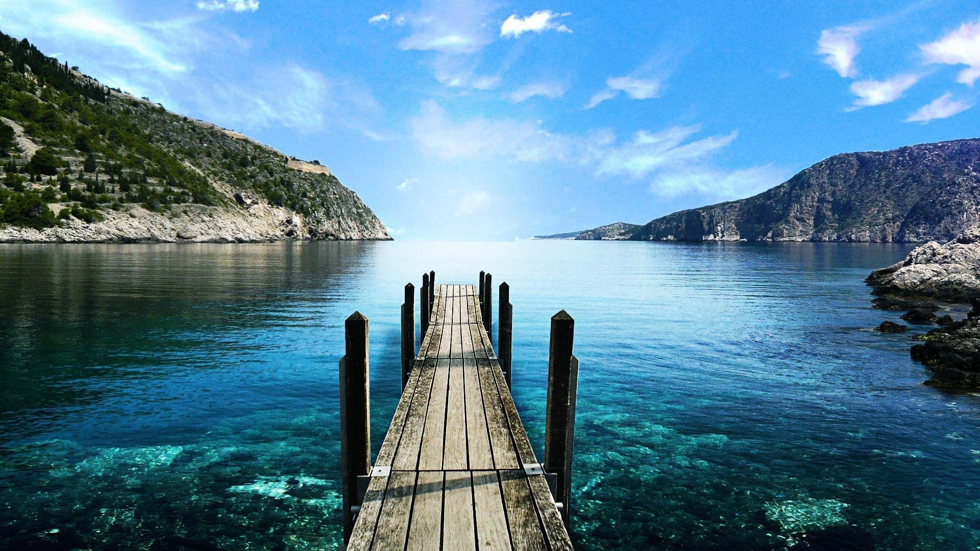 Wooden pier on a clear blue lake with mountains HD Wallpaper