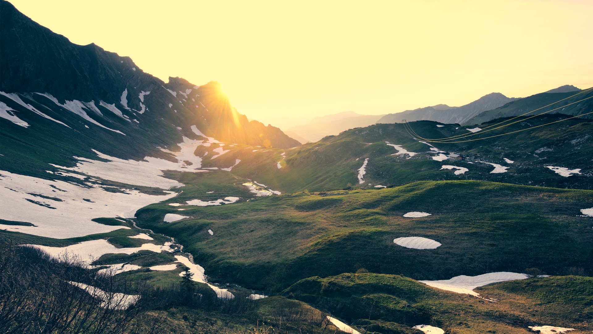 Mountain valley with sunset and snow patches HD Wallpaper