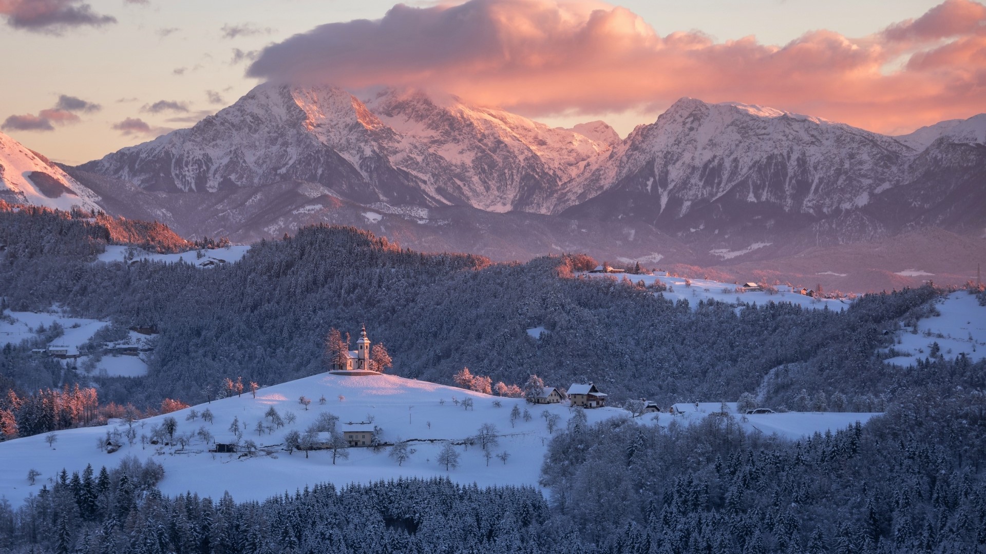 Snowy mountains with a church on a hill at sunset HD Wallpaper