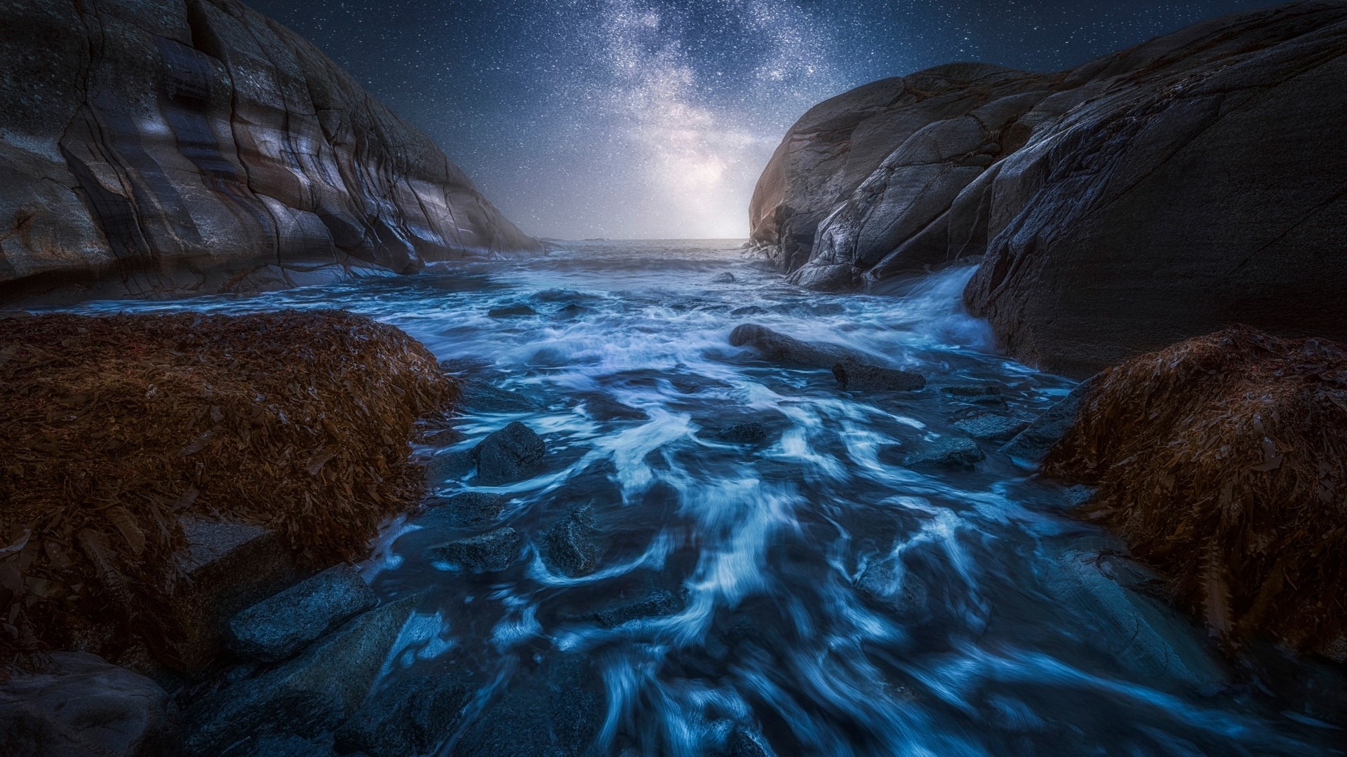 Ocean waves crashing between rocky cliffs under a starry sky HD Wallpaper