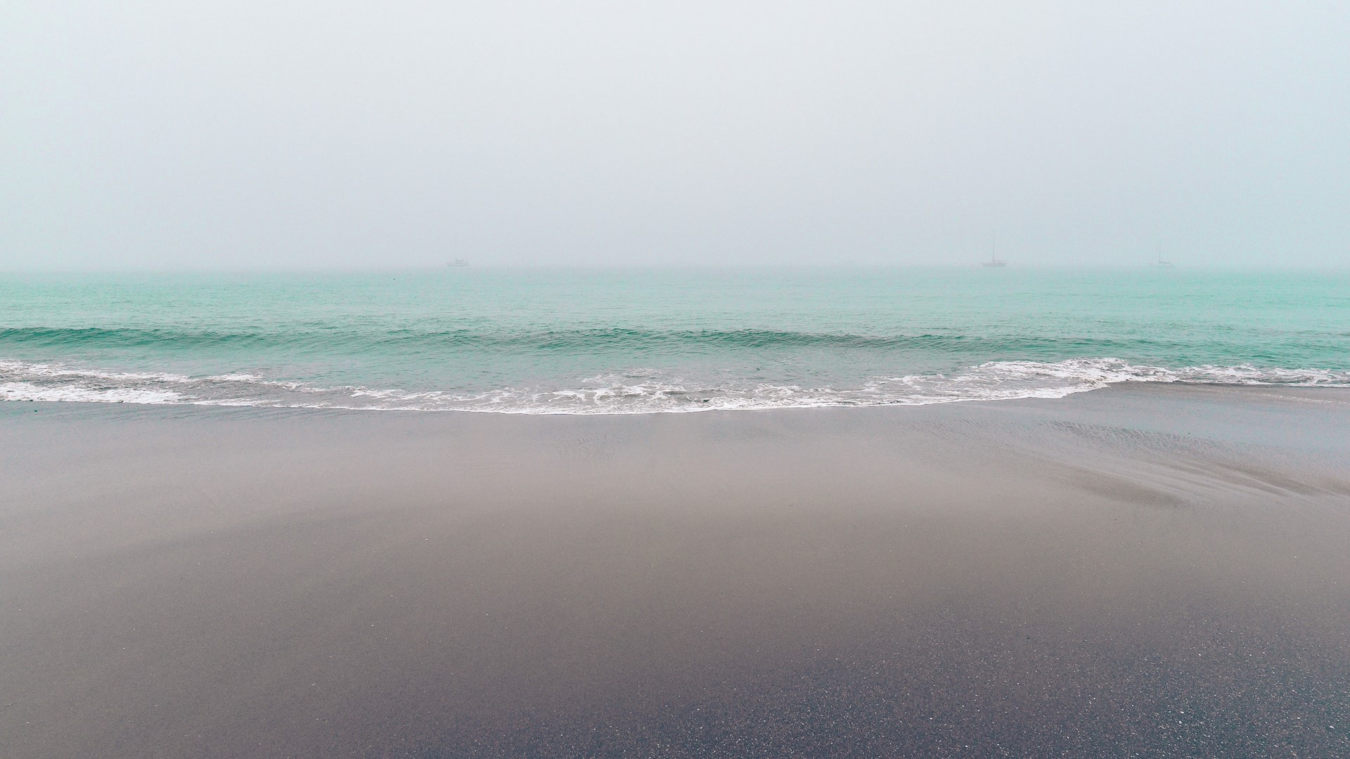Foggy coast with turquoise water and boats HD Wallpaper