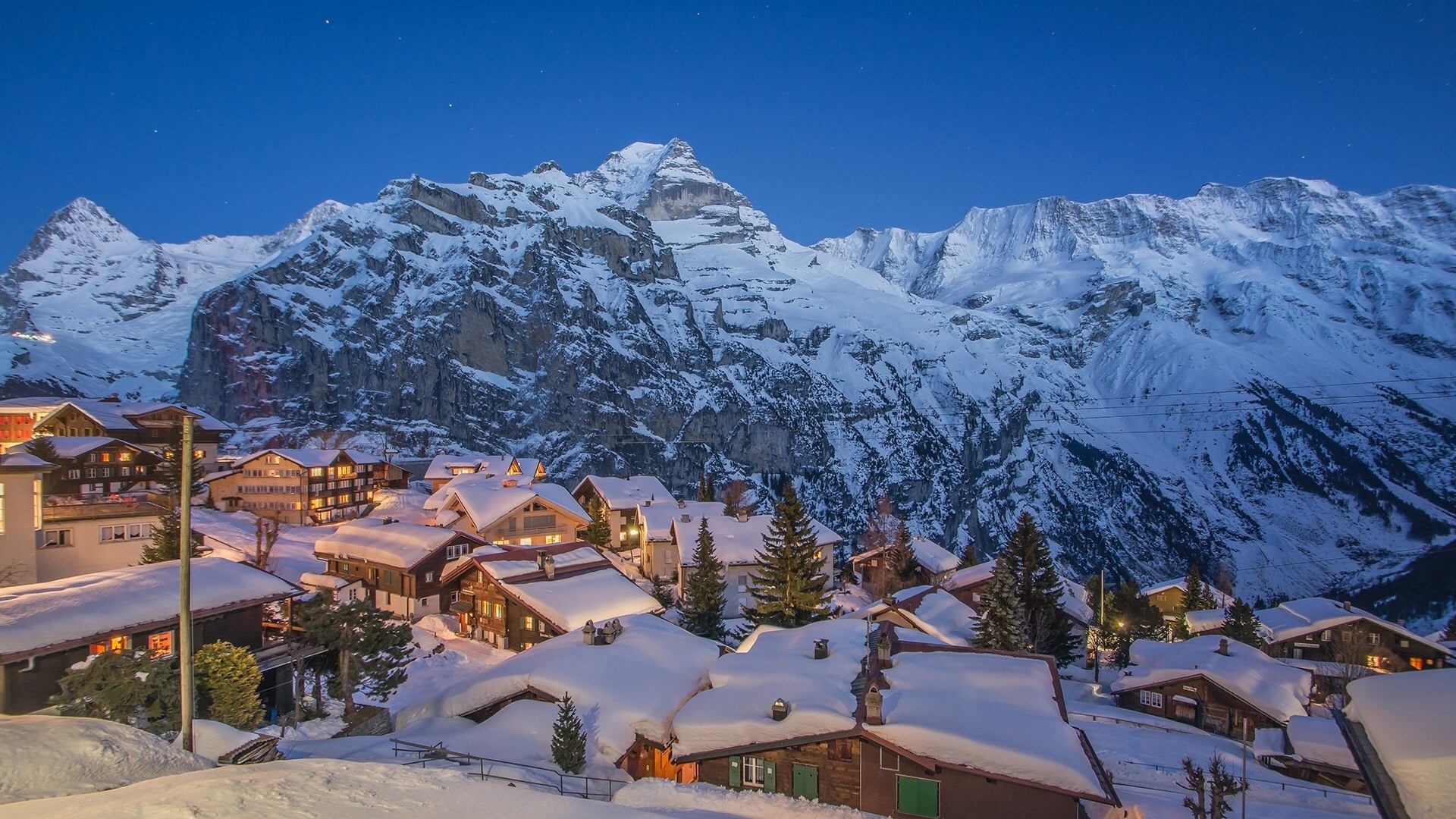 Snowy Swiss village at dusk with mountains HD Wallpaper