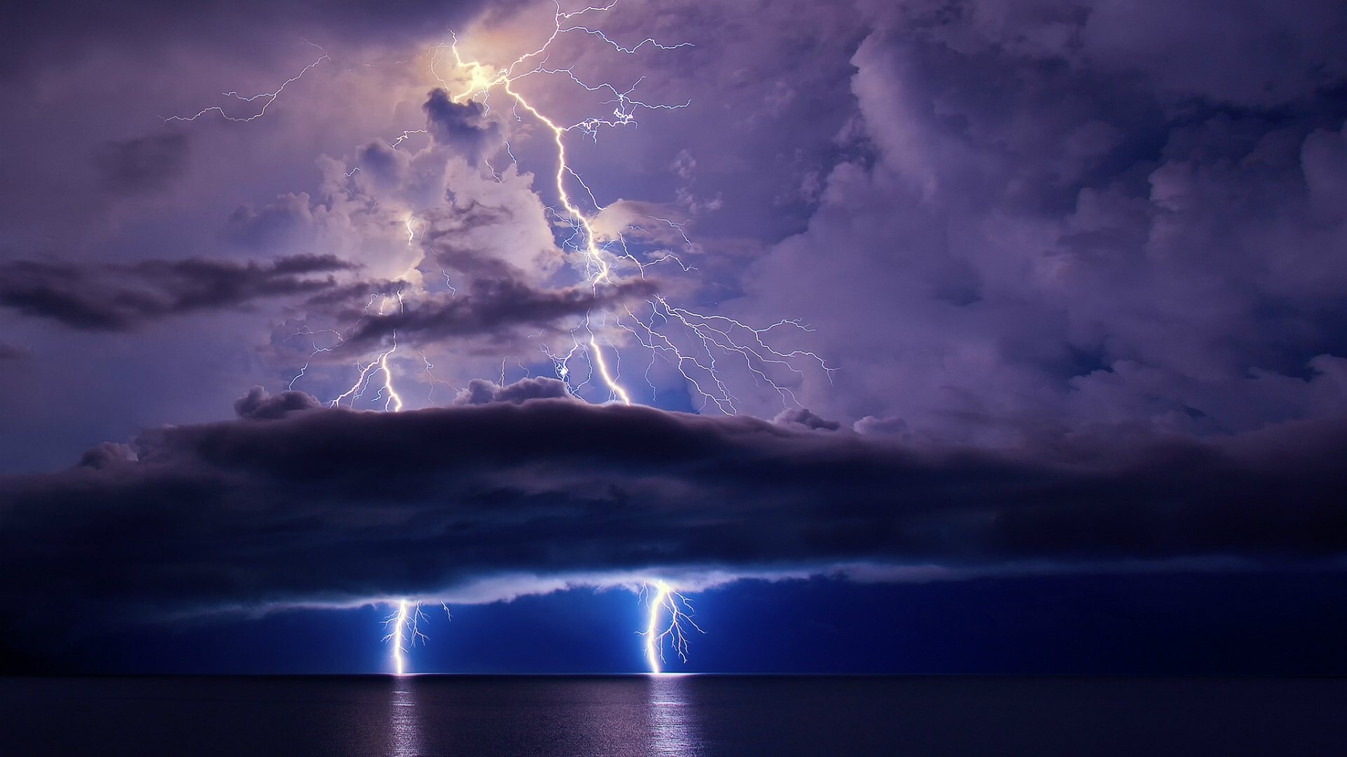 Lightning strikes over the ocean during a thunderstorm HD Wallpaper