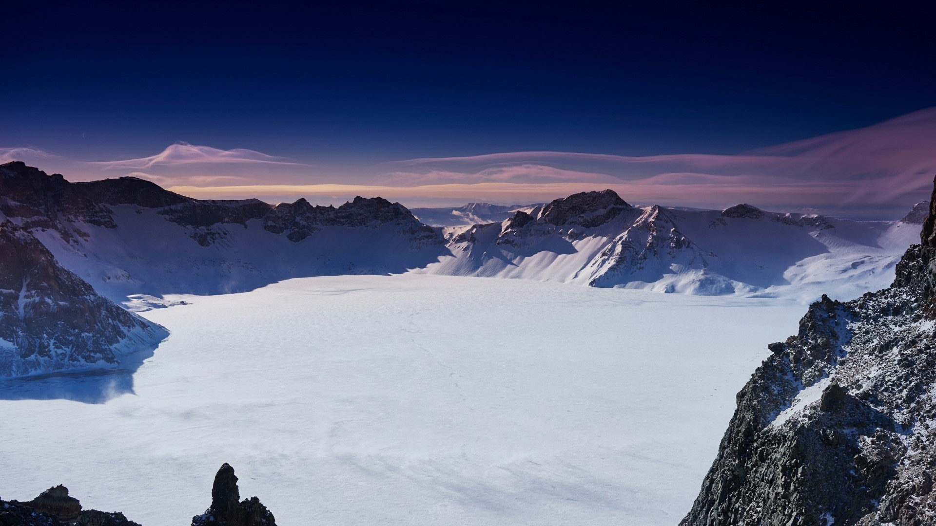 Frozen mountain lake with snow-covered peaks HD Wallpaper