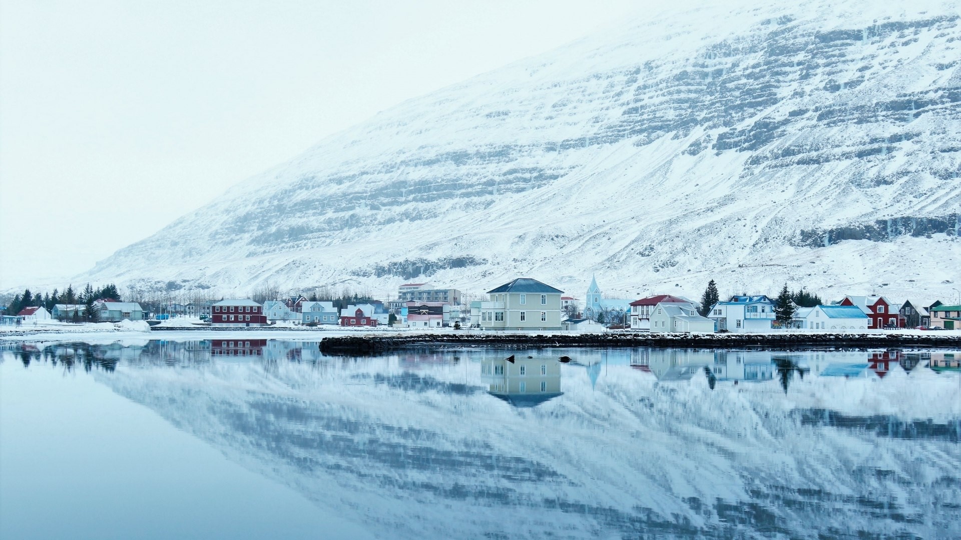 Snowy Icelandic village reflected in water HD Wallpaper