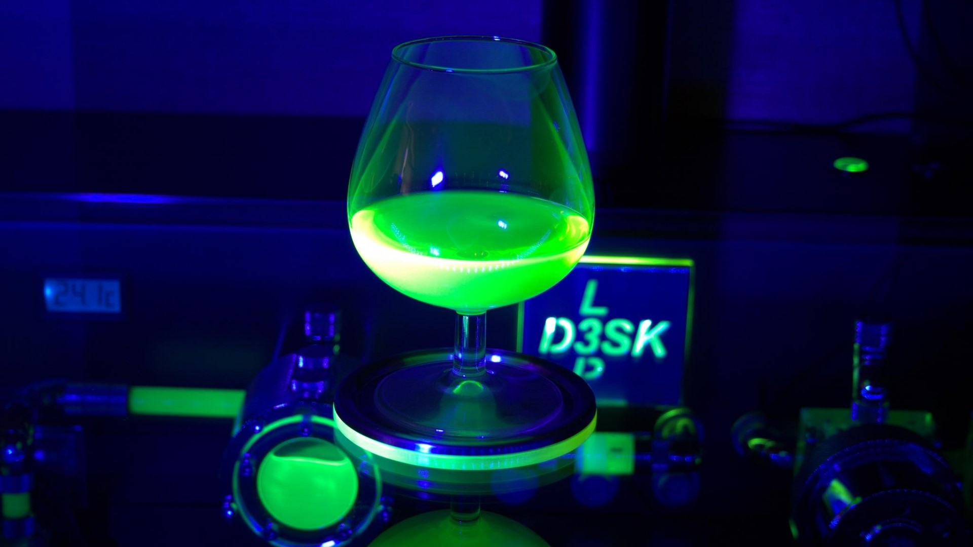 Glass of glowing liquid under blacklight HD Wallpaper
