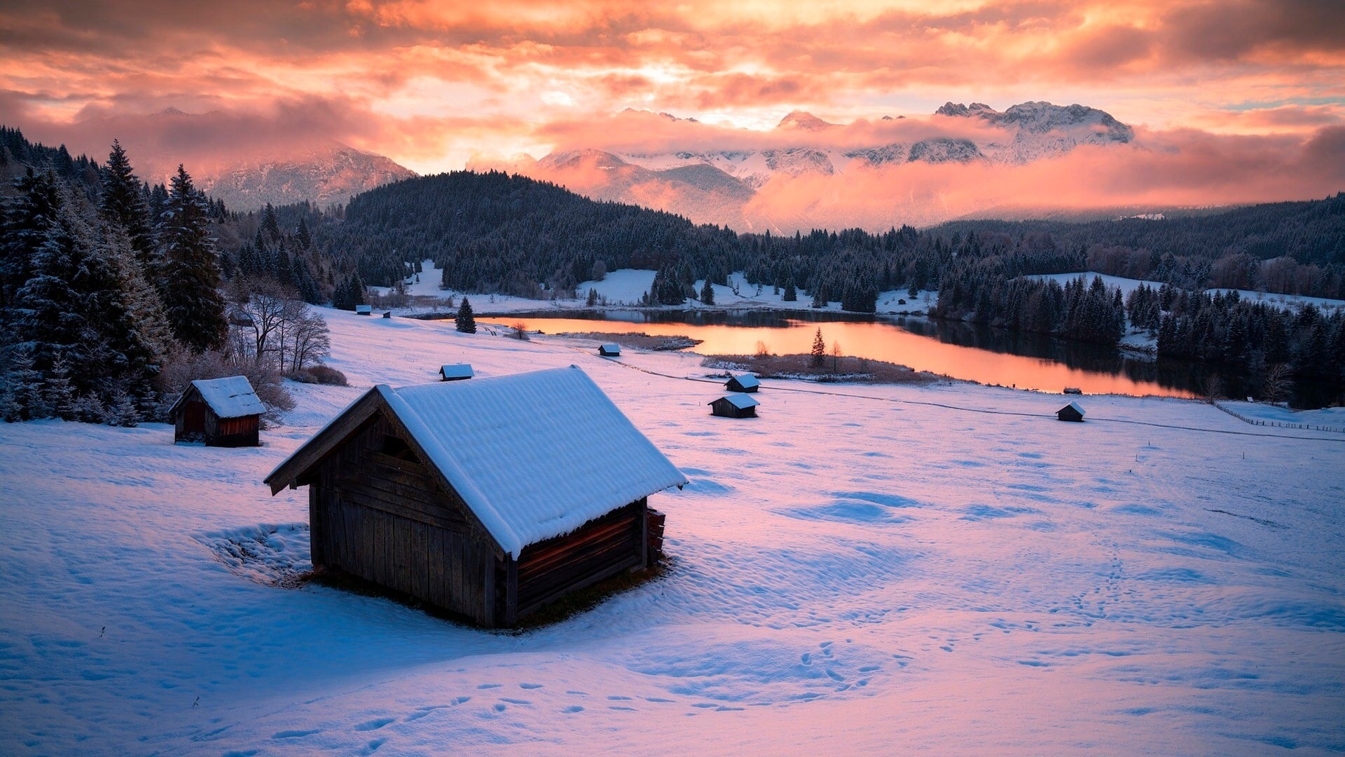 Snowy landscape with cabins and mountains at sunset HD Wallpaper