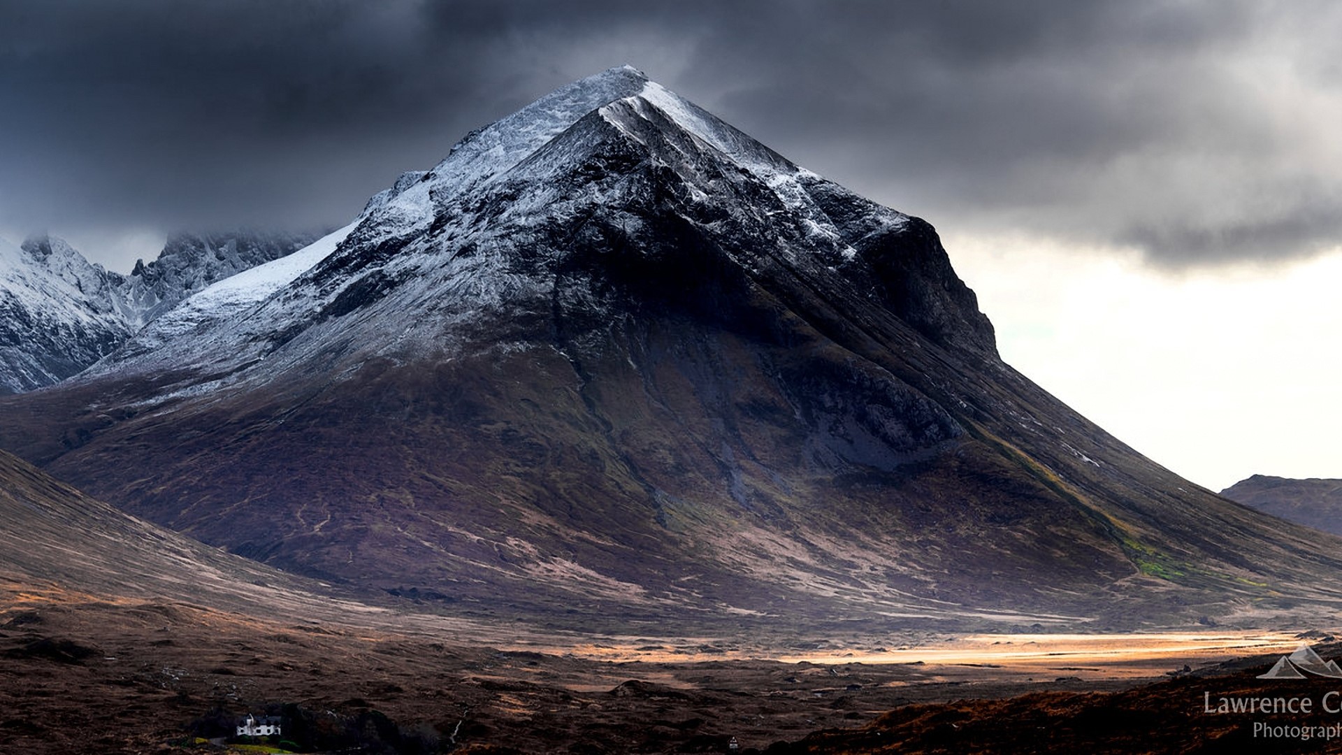 Snow-capped mountain range under stormy skies HD Wallpaper