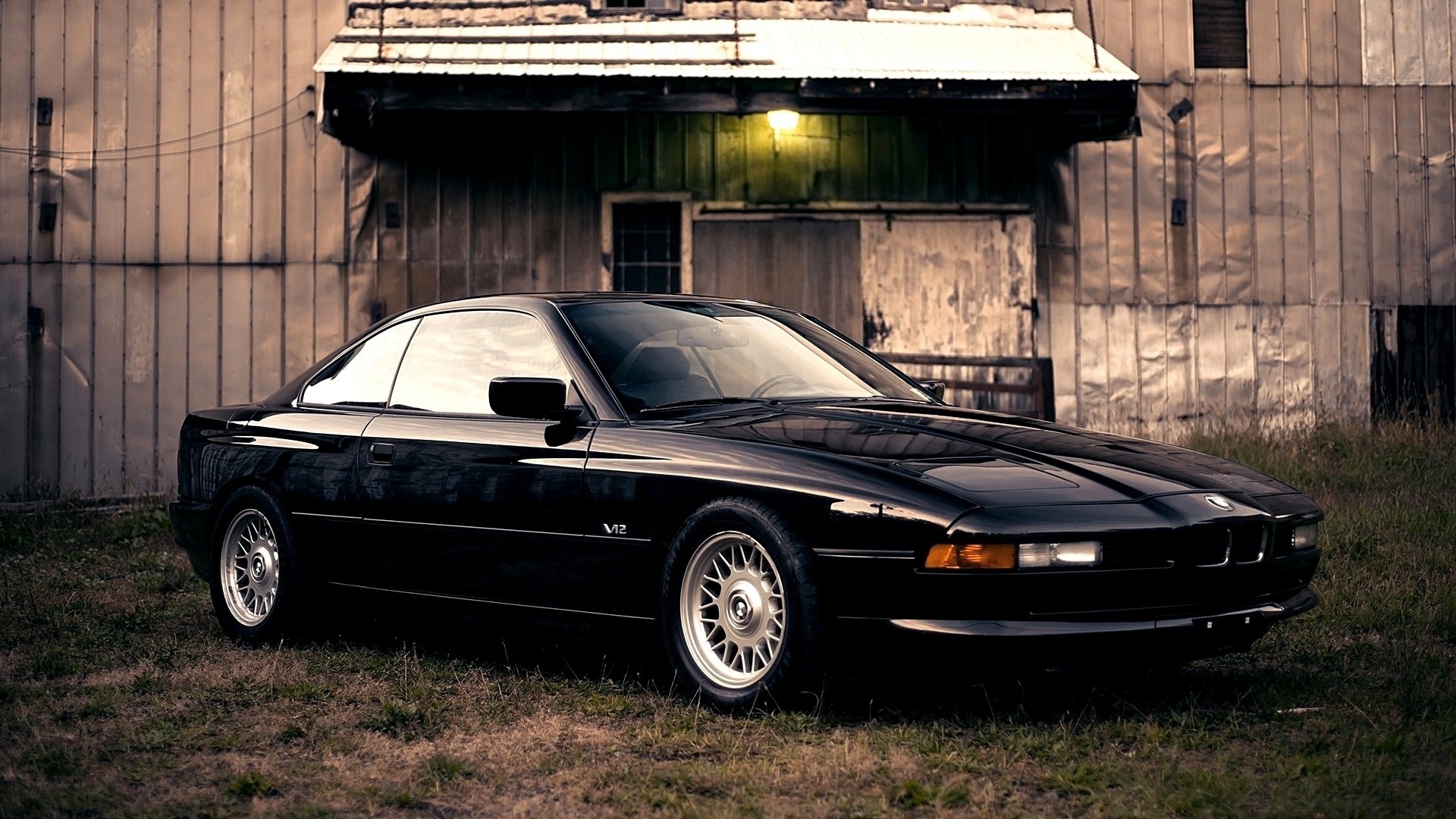 Black BMW 850i parked in front of a weathered building HD Wallpaper