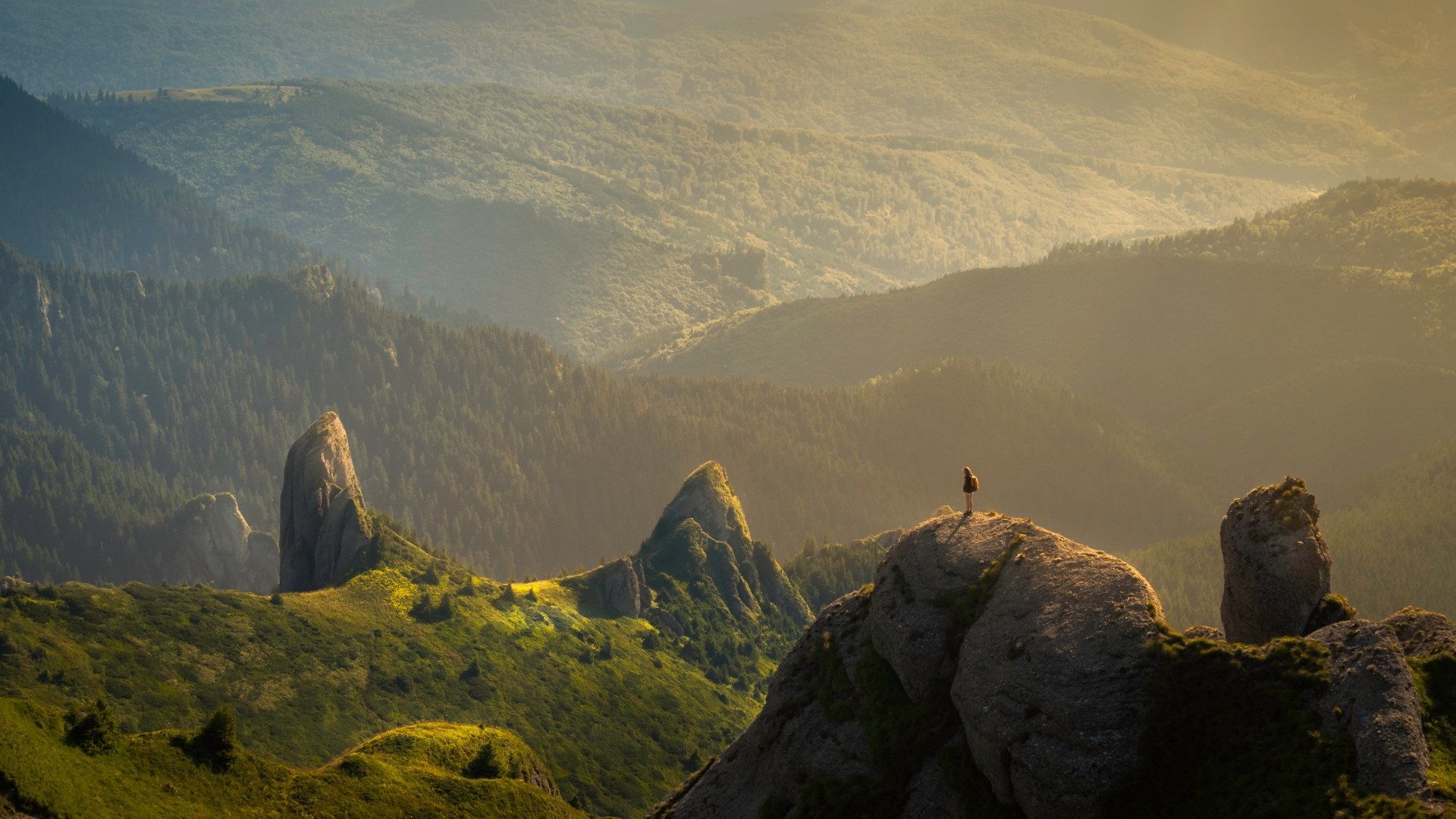 Person standing on a mountain peak at sunrise HD Wallpaper
