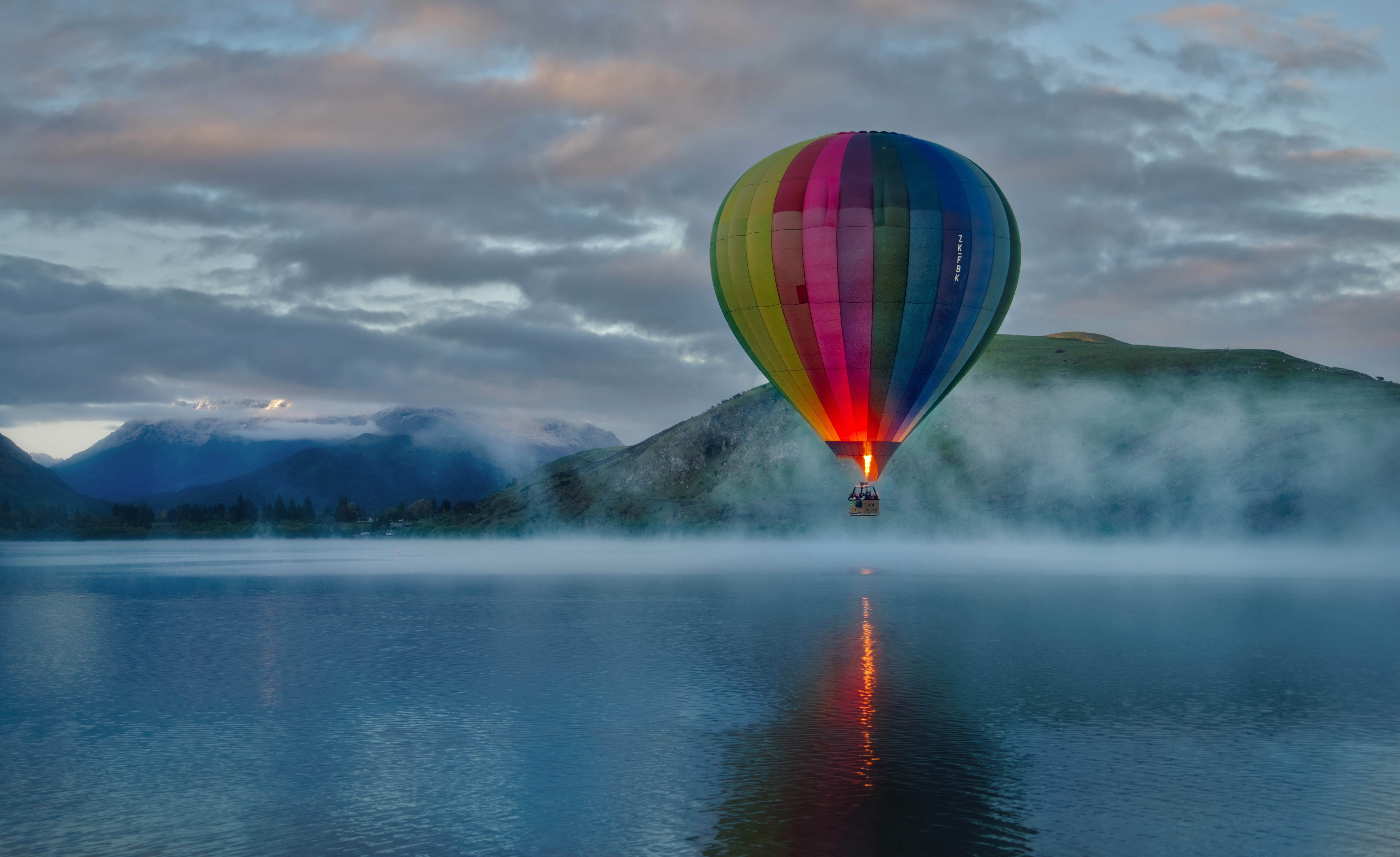 Hot air balloon over misty lake at sunrise HD Wallpaper