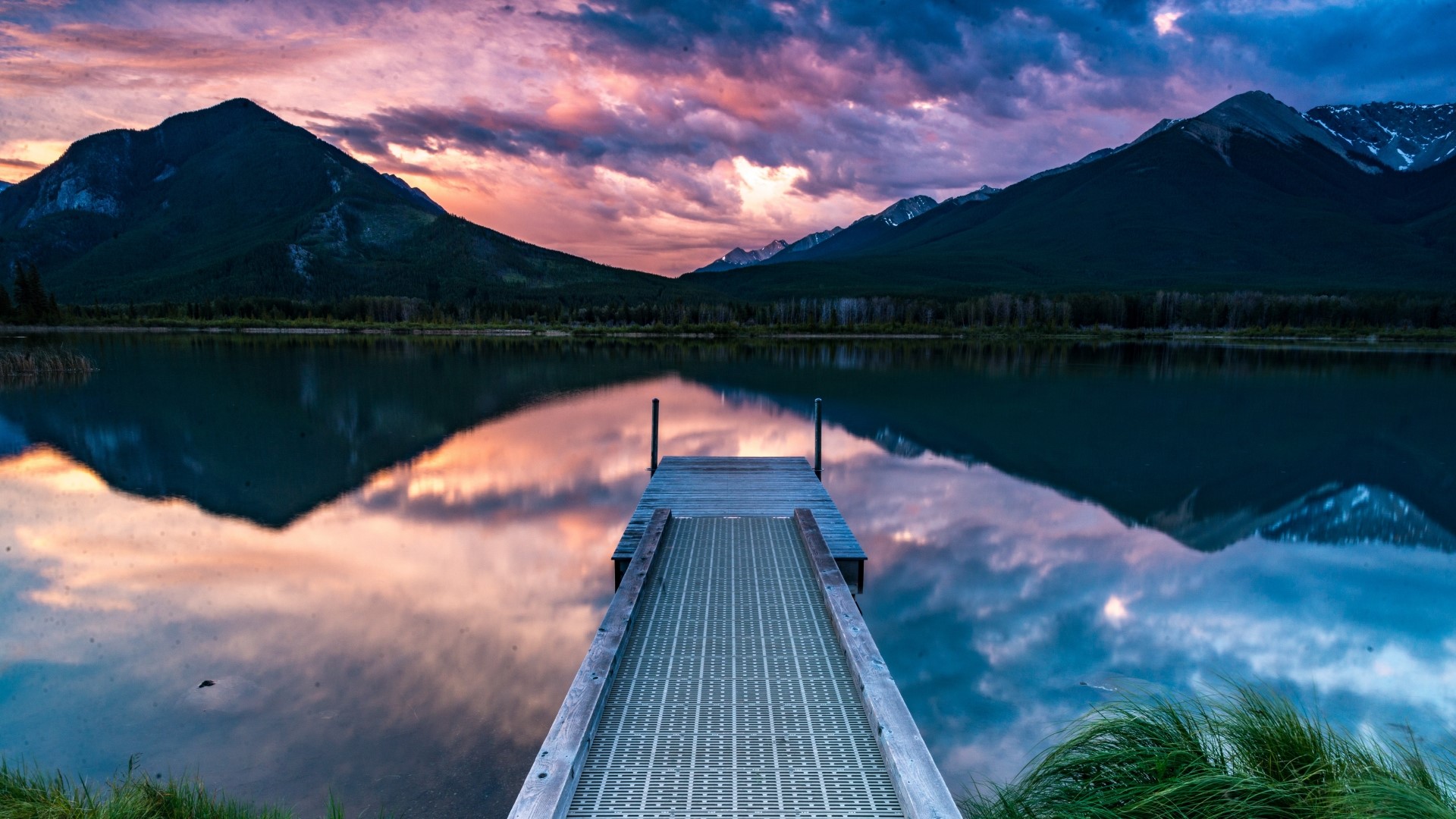 Sunset over a lake with a pier and mountains HD Wallpaper