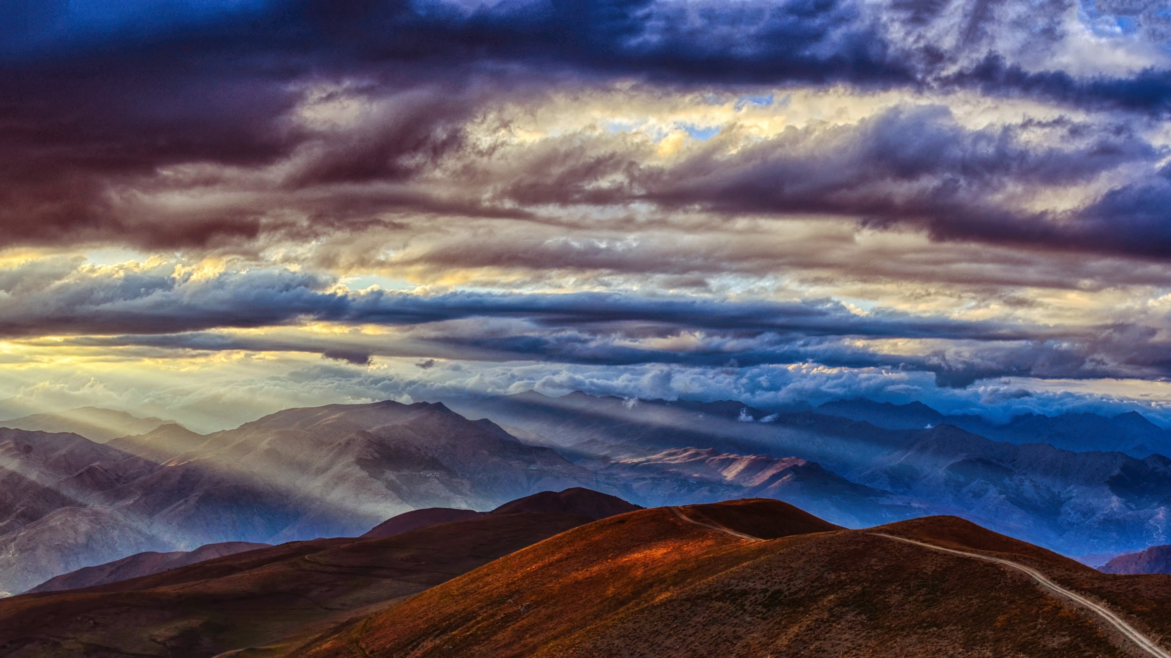 Sunbeams through dramatic clouds over mountain ranges HD Wallpaper
