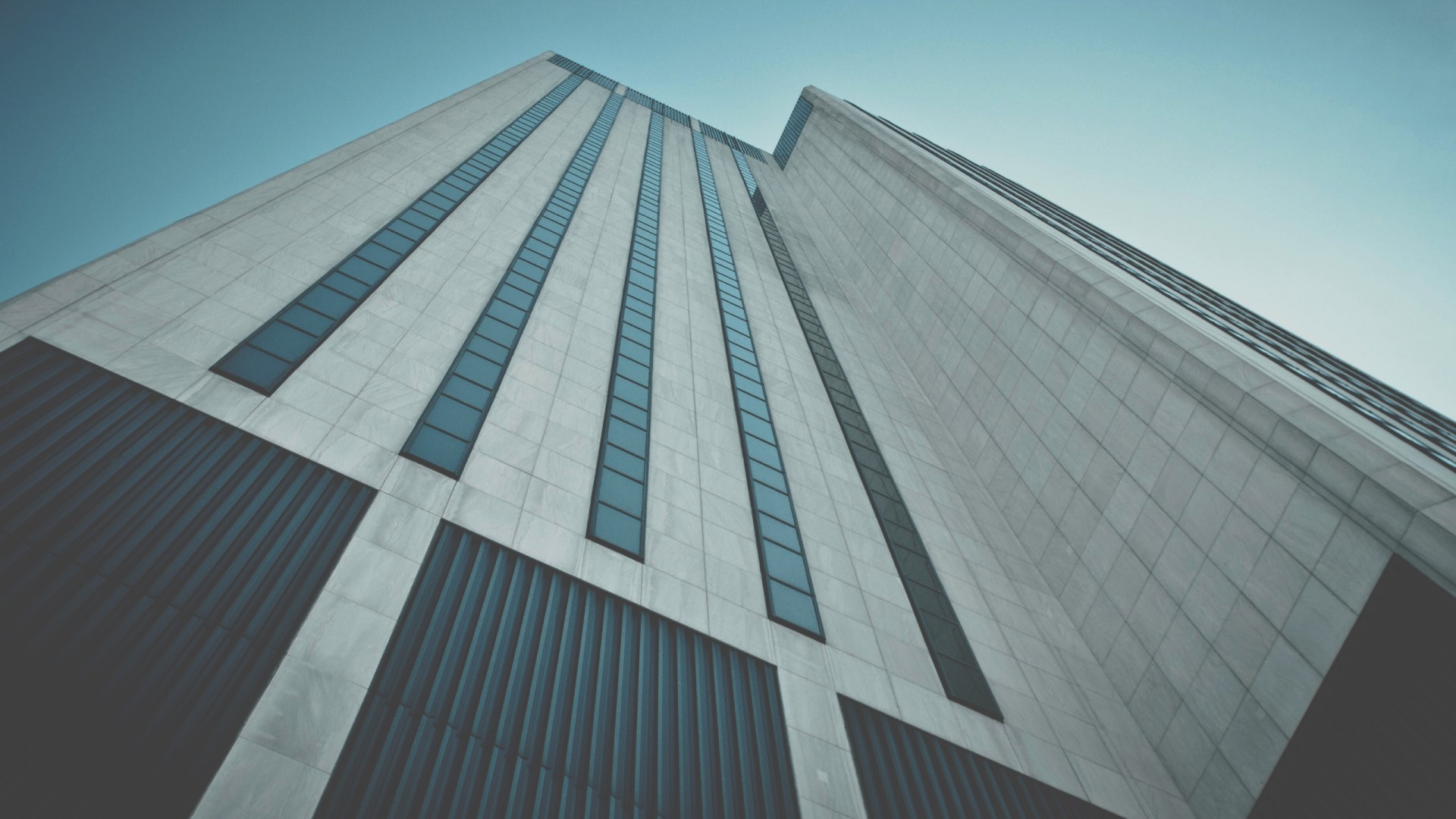 Modern skyscraper with glass windows against blue sky HD Wallpaper