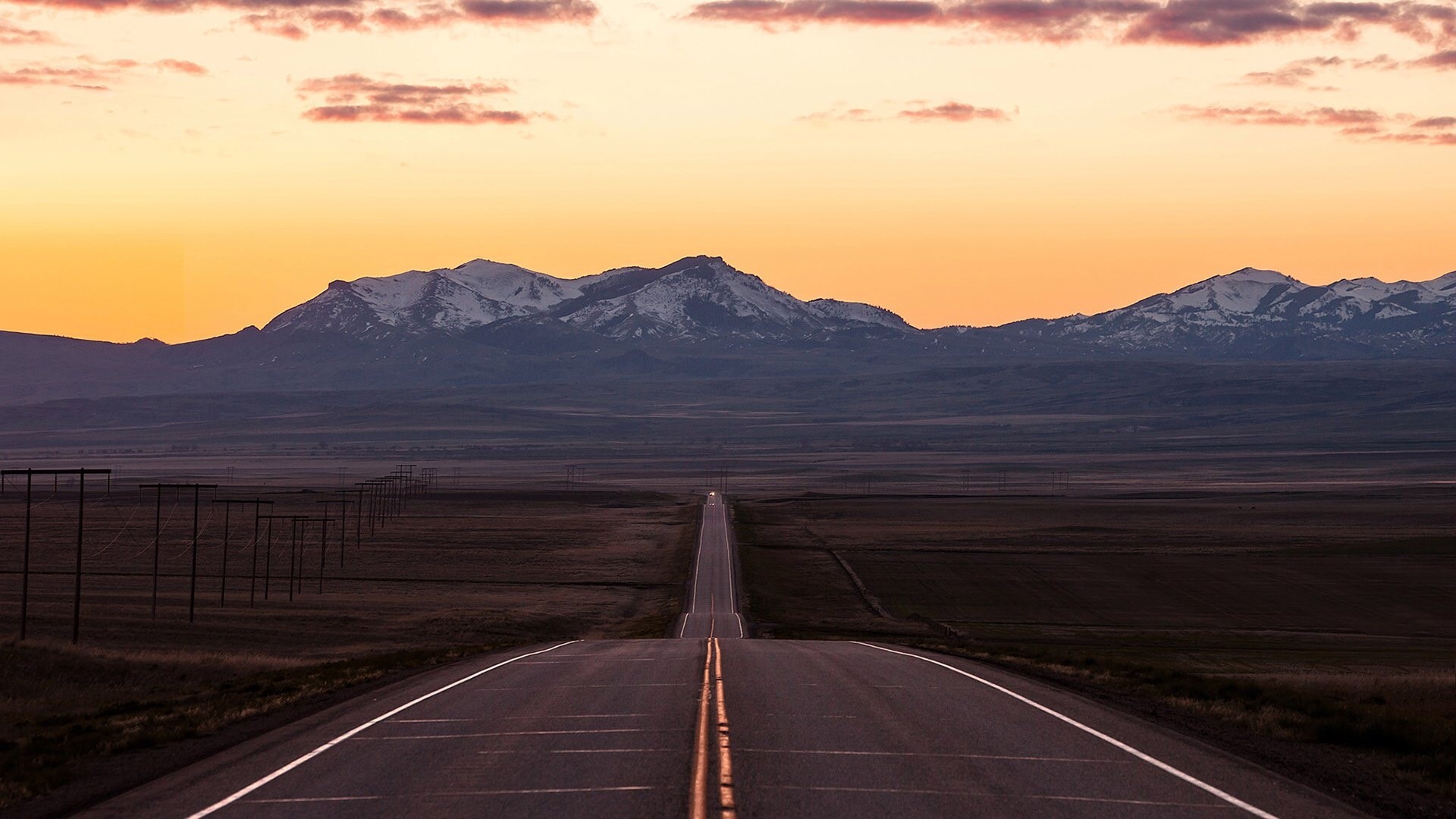 Road leading to snow-capped mountains at sunset HD Wallpaper