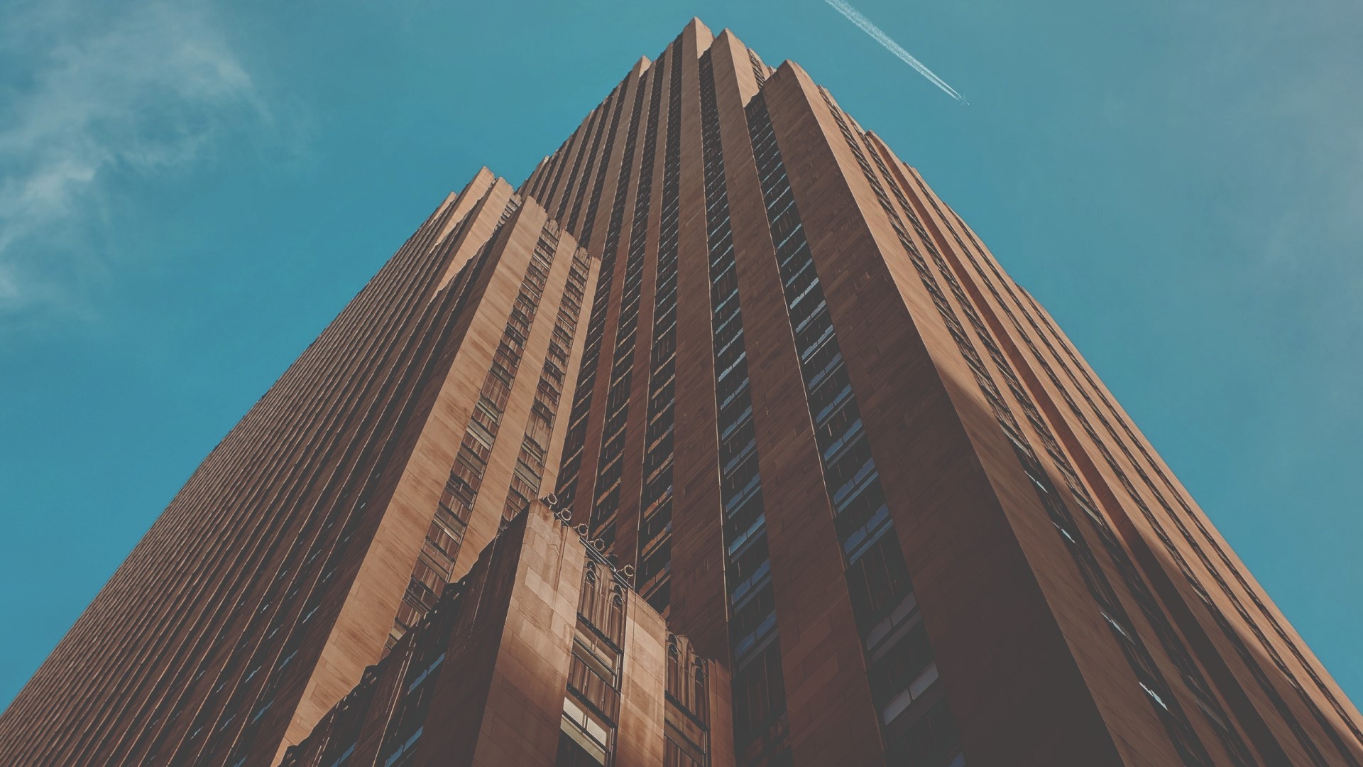 Tall brown skyscraper against a blue sky HD Wallpaper