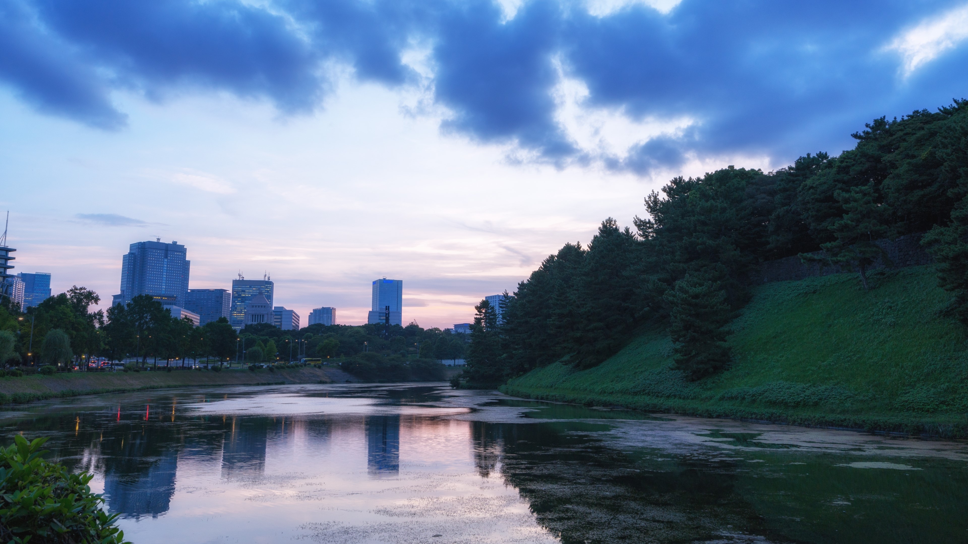 Body of Water and Green Hills with Cityscape HD Wallpaper
