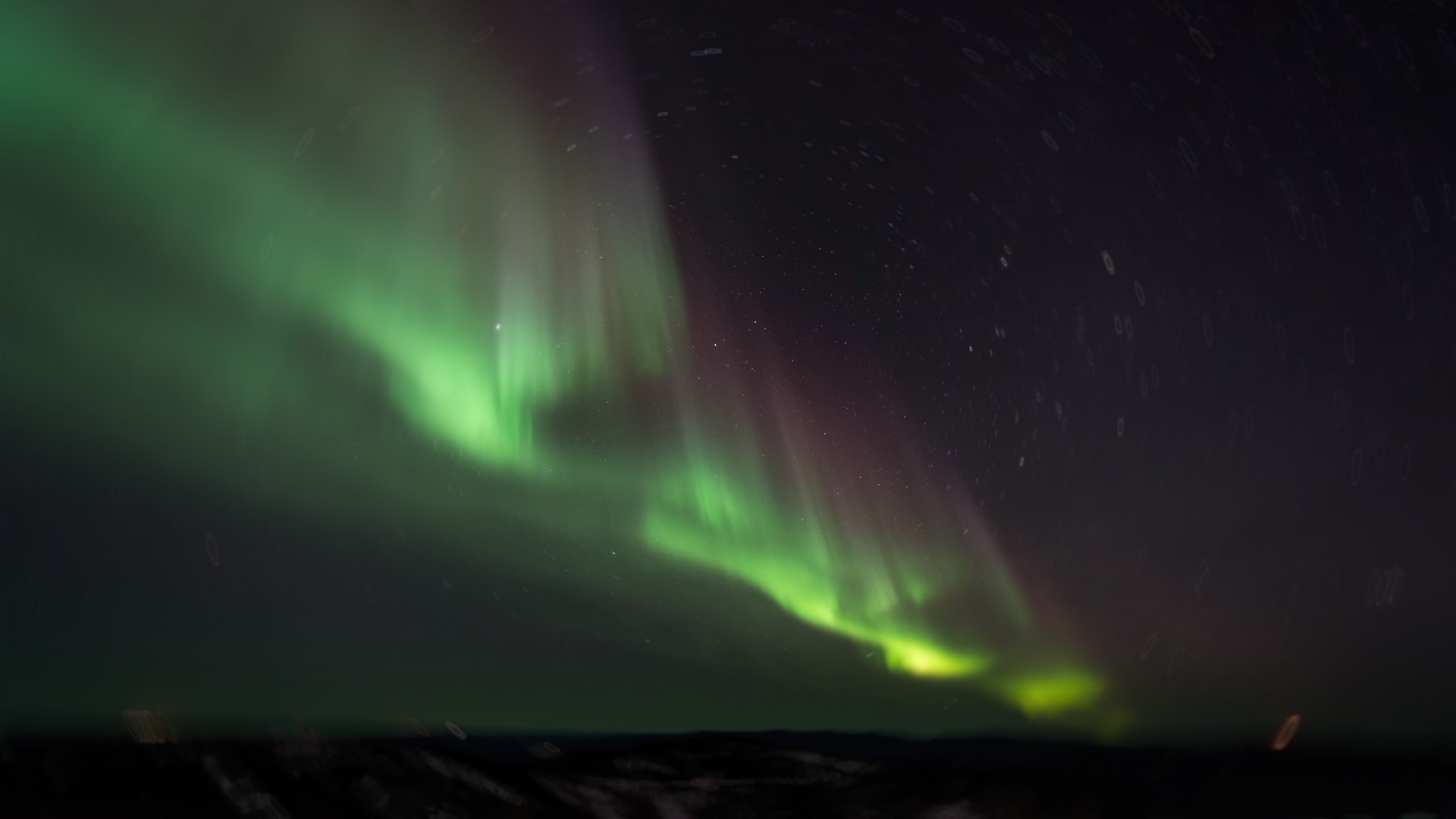 Aurora Borealis over a dark landscape HD Wallpaper
