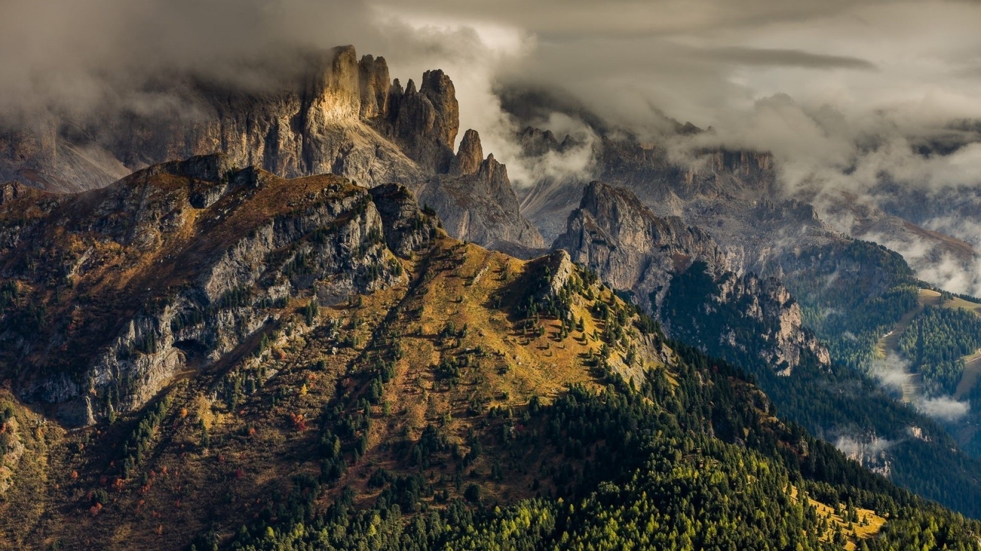 Jagged mountain peaks shrouded in clouds HD Wallpaper