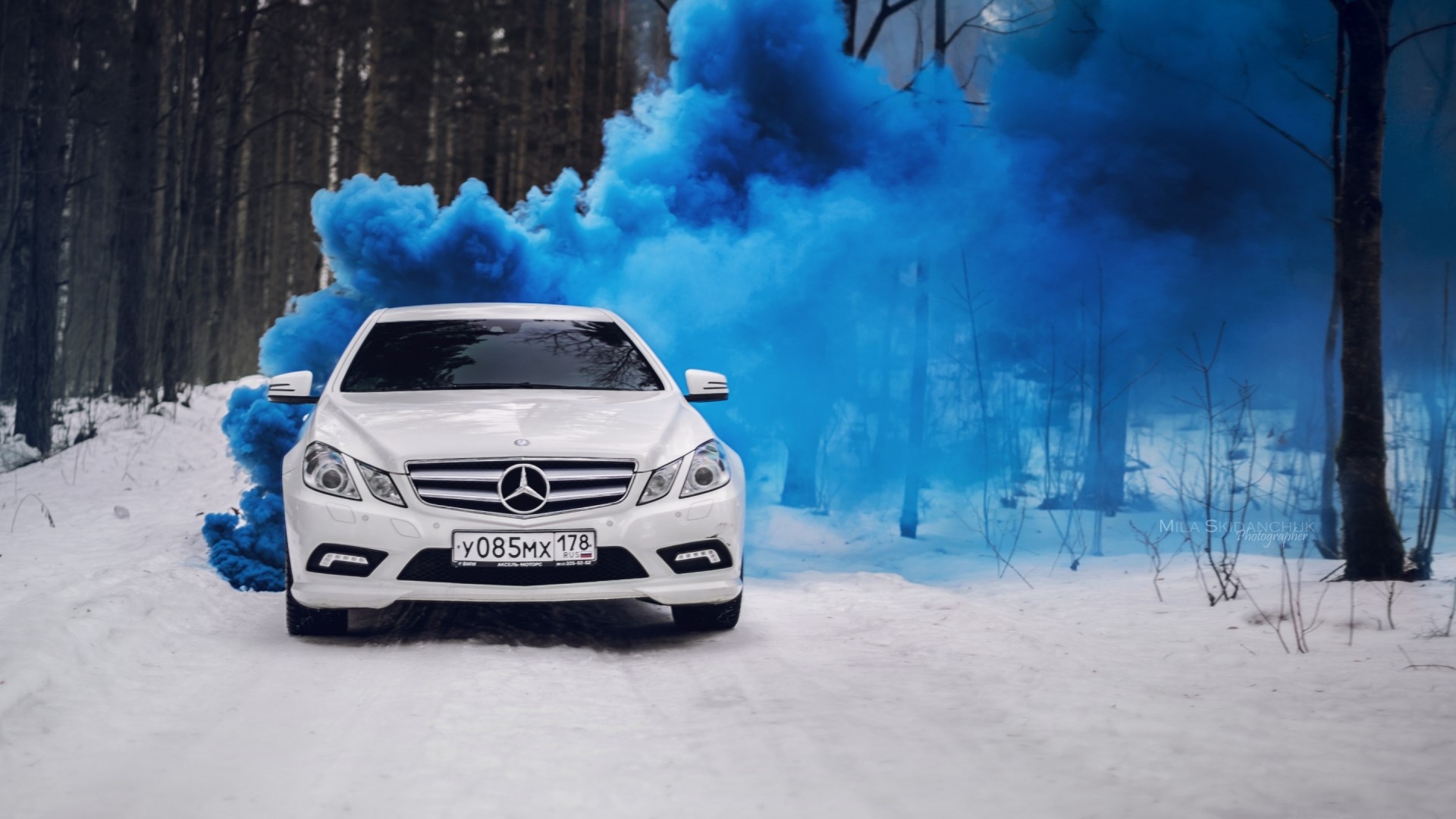 White Mercedes-Benz E-Class with blue smoke in snowy forest HD Wallpaper