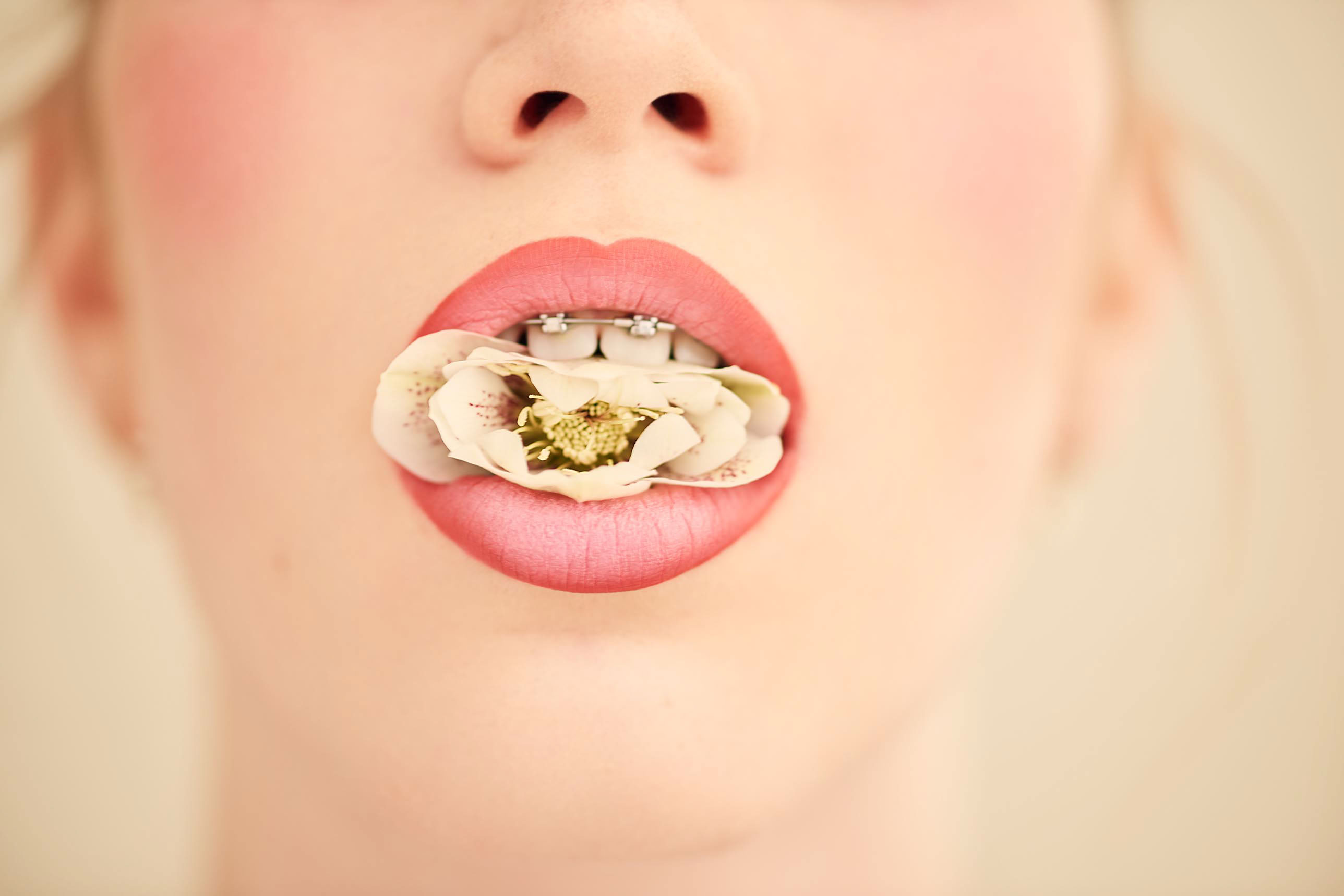 Woman with flower in mouth and braces HD Wallpaper
