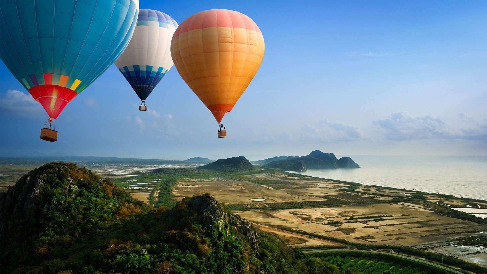 Hot air balloons over a coastal landscape HD Wallpaper