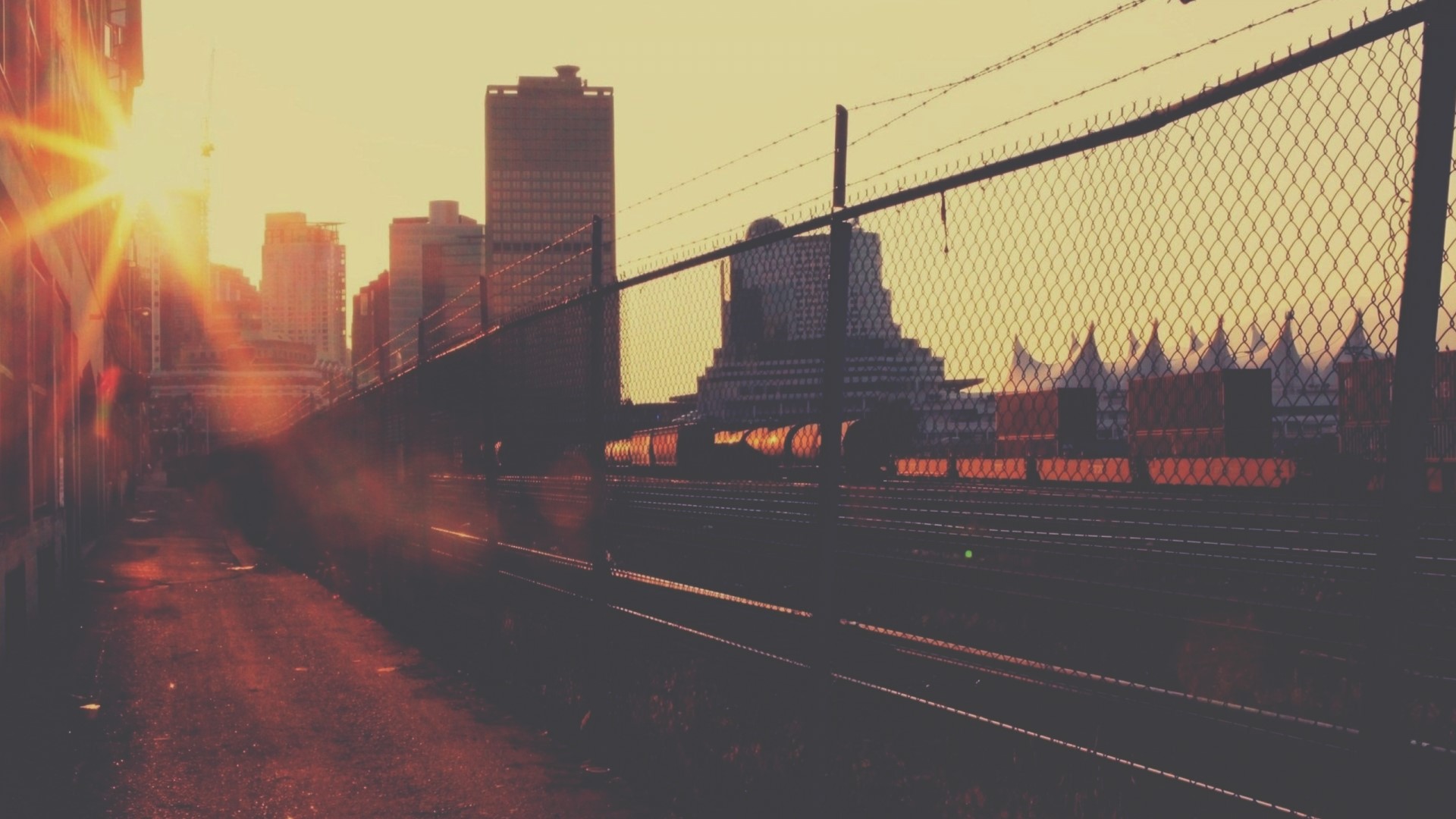 Sunrise over city with train tracks and fence HD Wallpaper