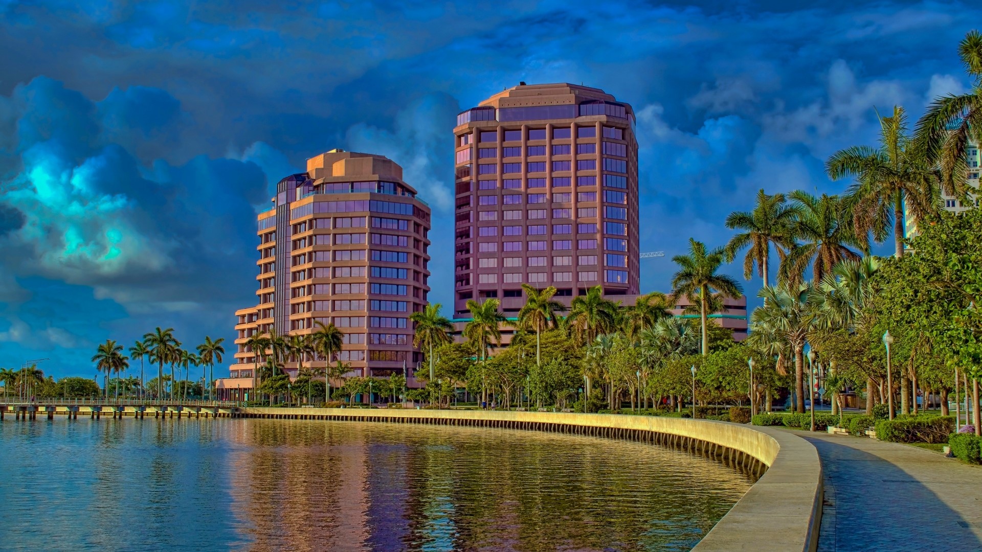 Two modern buildings by a waterfront with palm trees HD Wallpaper