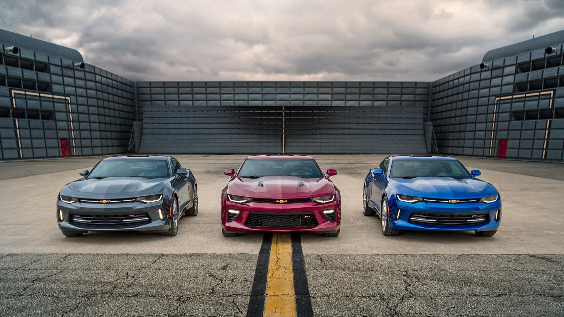 Three Chevrolet Camaros parked in front of a building HD Wallpaper