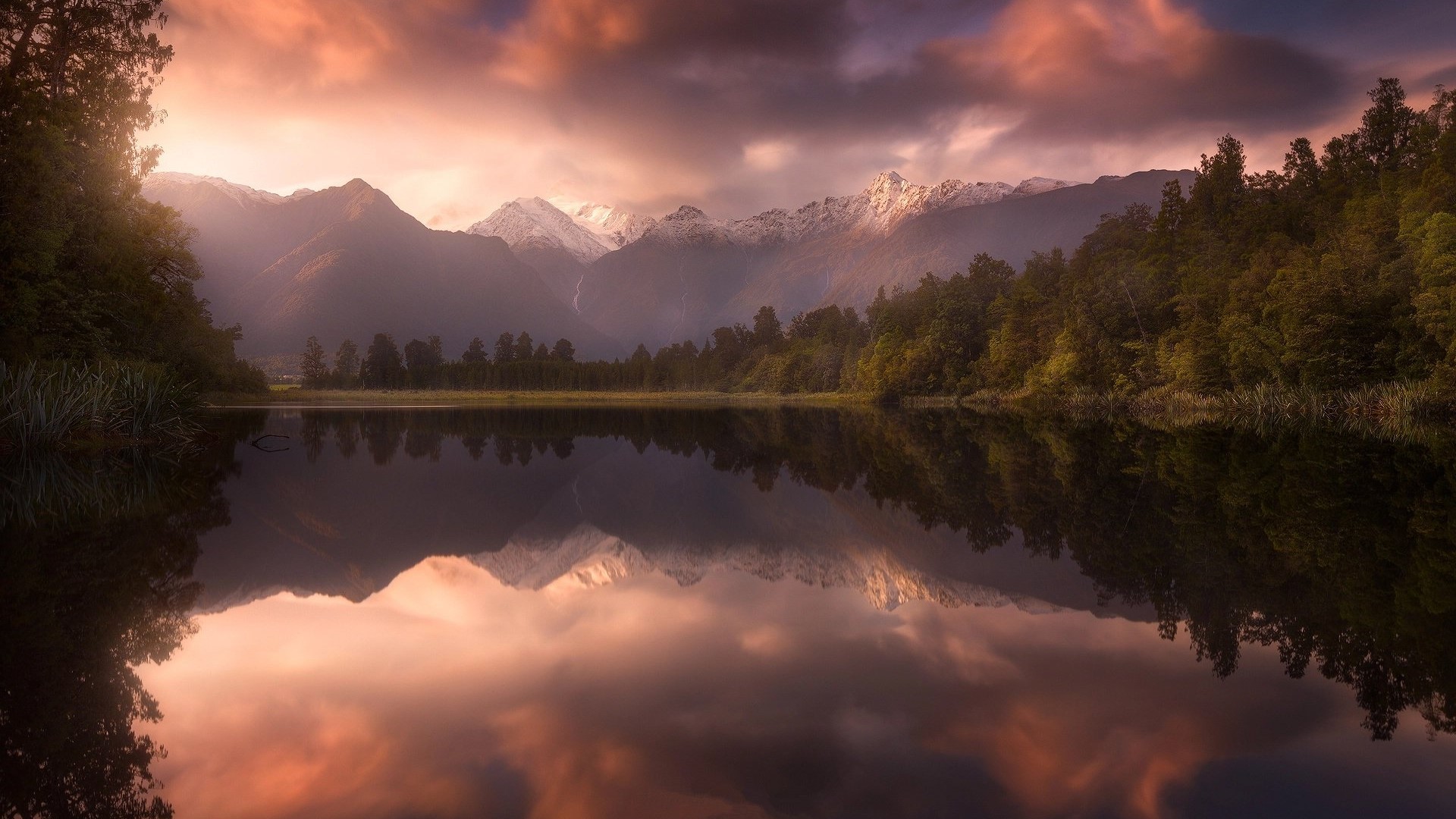 Lake reflecting mountains and forest at sunset HD Wallpaper