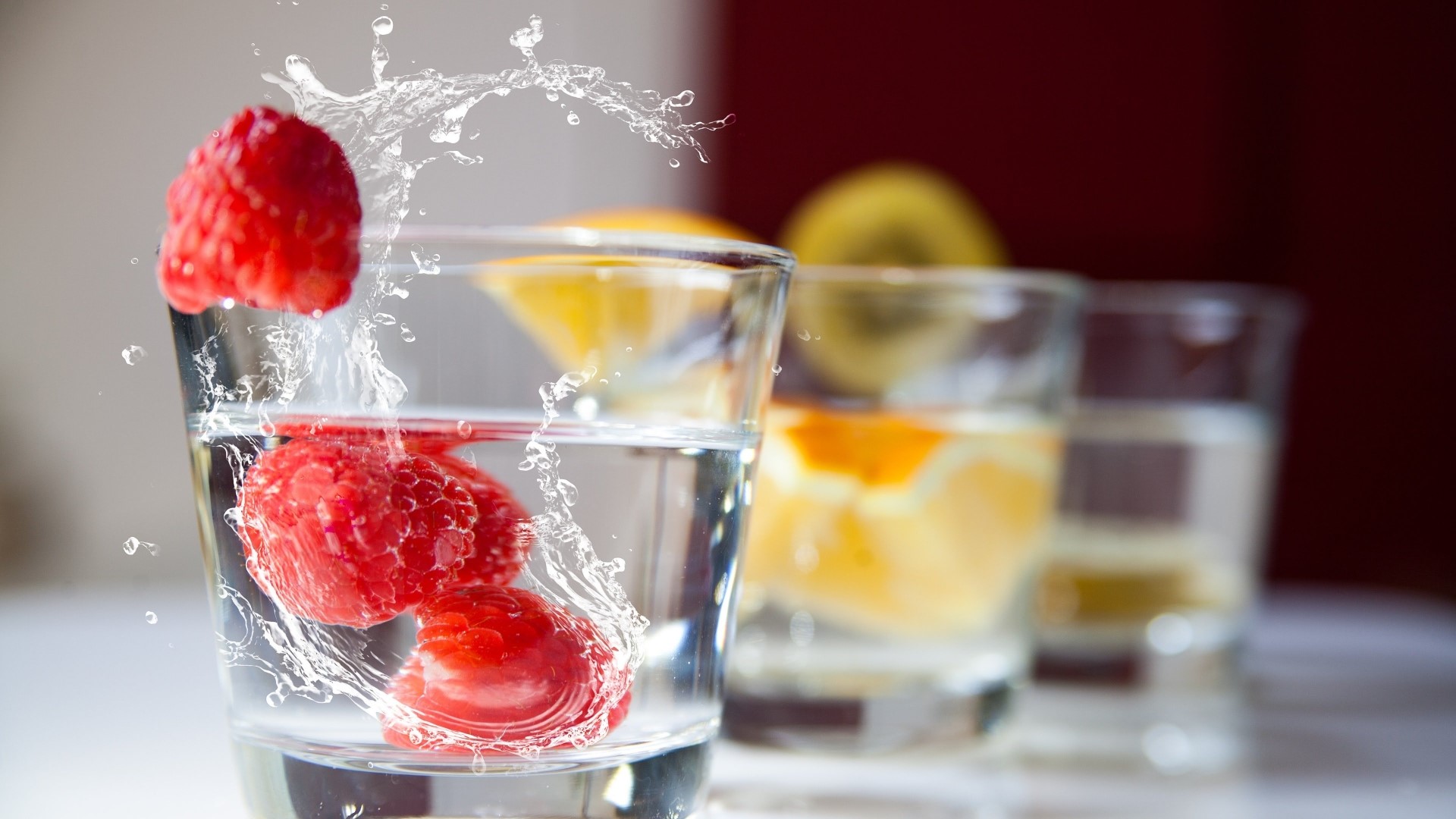 Raspberries and fruit slices in glasses of water HD Wallpaper