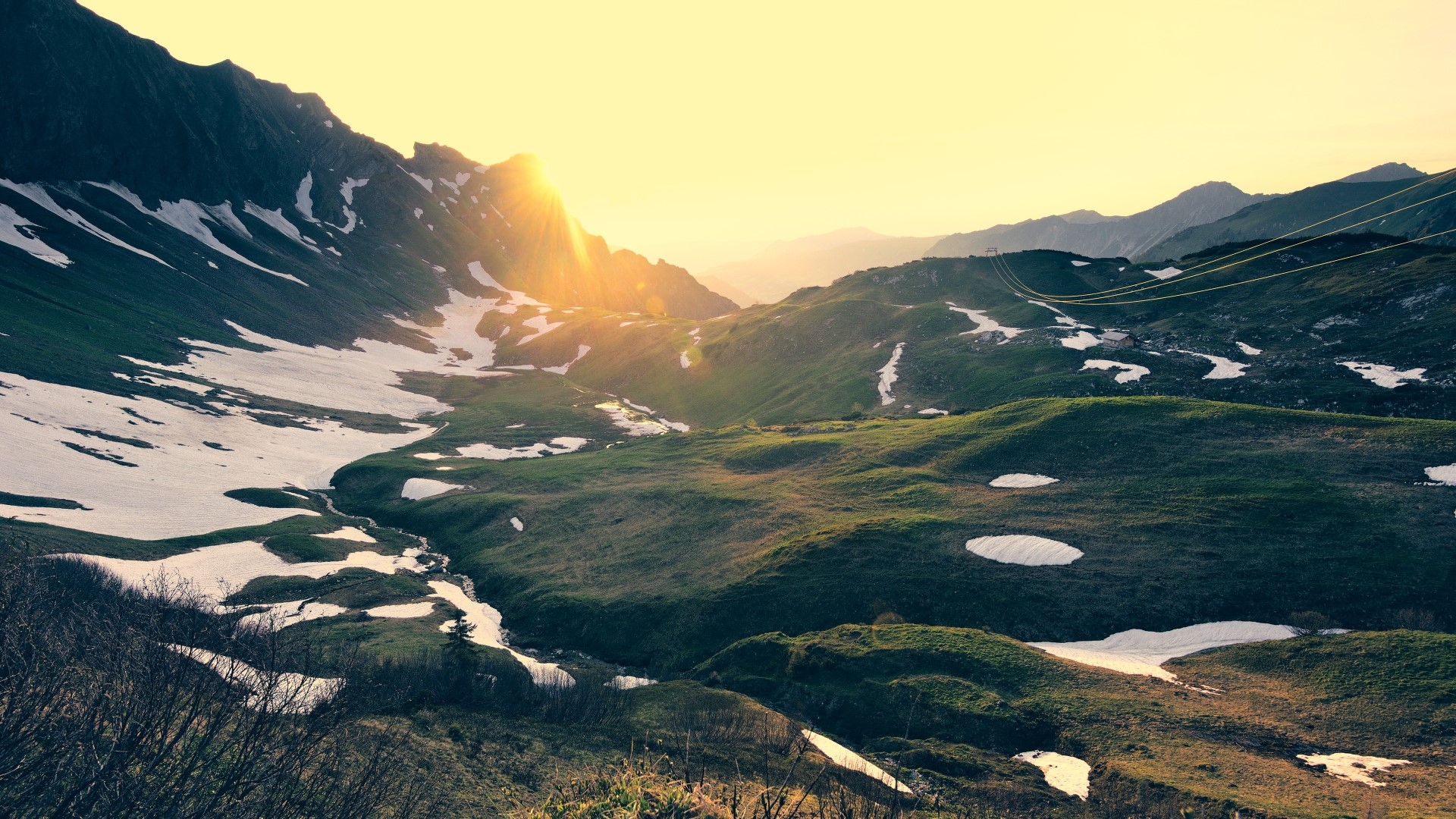 Mountain valley with snow patches at sunset HD Wallpaper